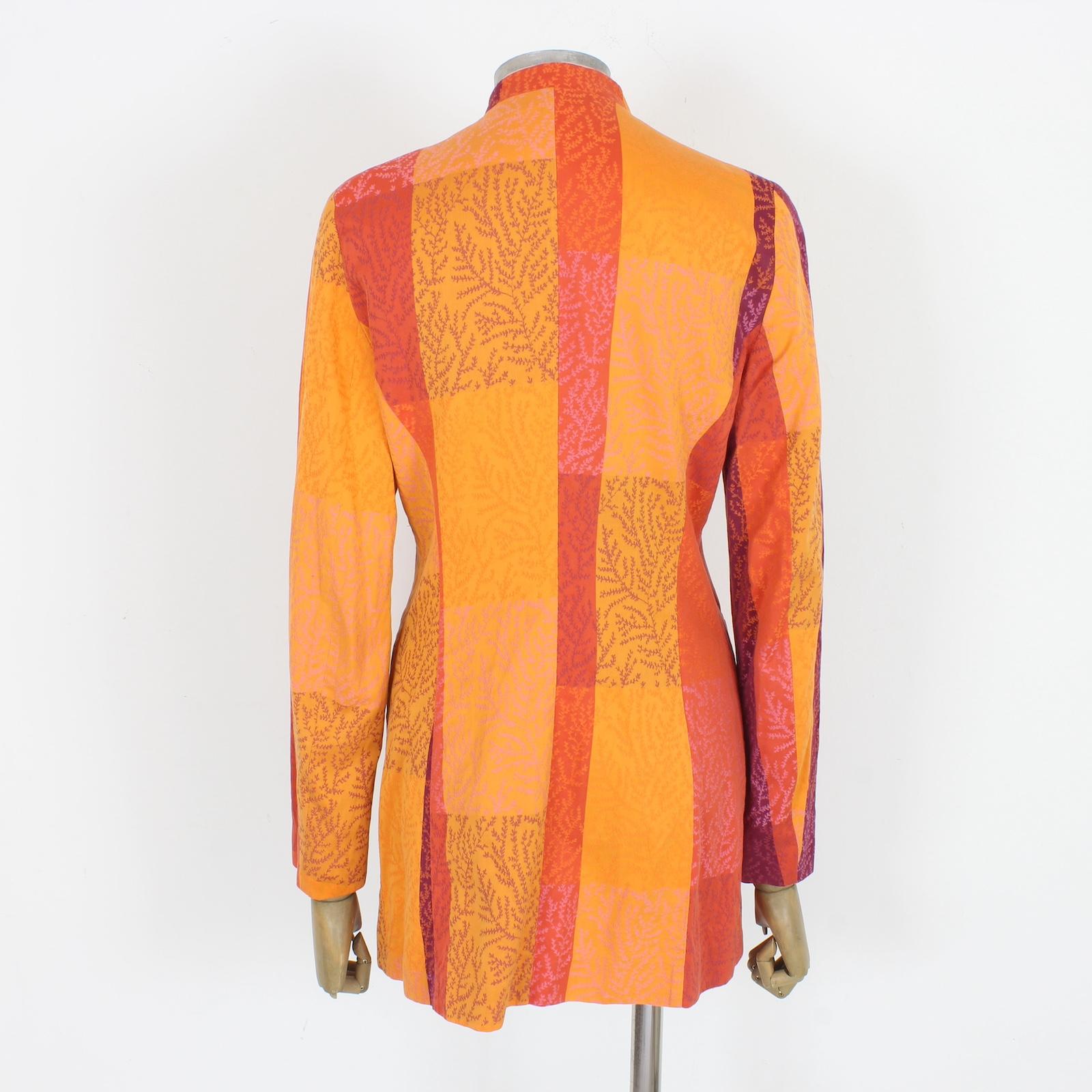 This vintage Kenzo orange cotton long jacket from the 80s is a must-have for any fashion enthusiast. Featuring a vibrant orange and fuchsia floral design, a Mandarin collar, and made of soft and comfortable cotton fabric, this jacket is the perfect