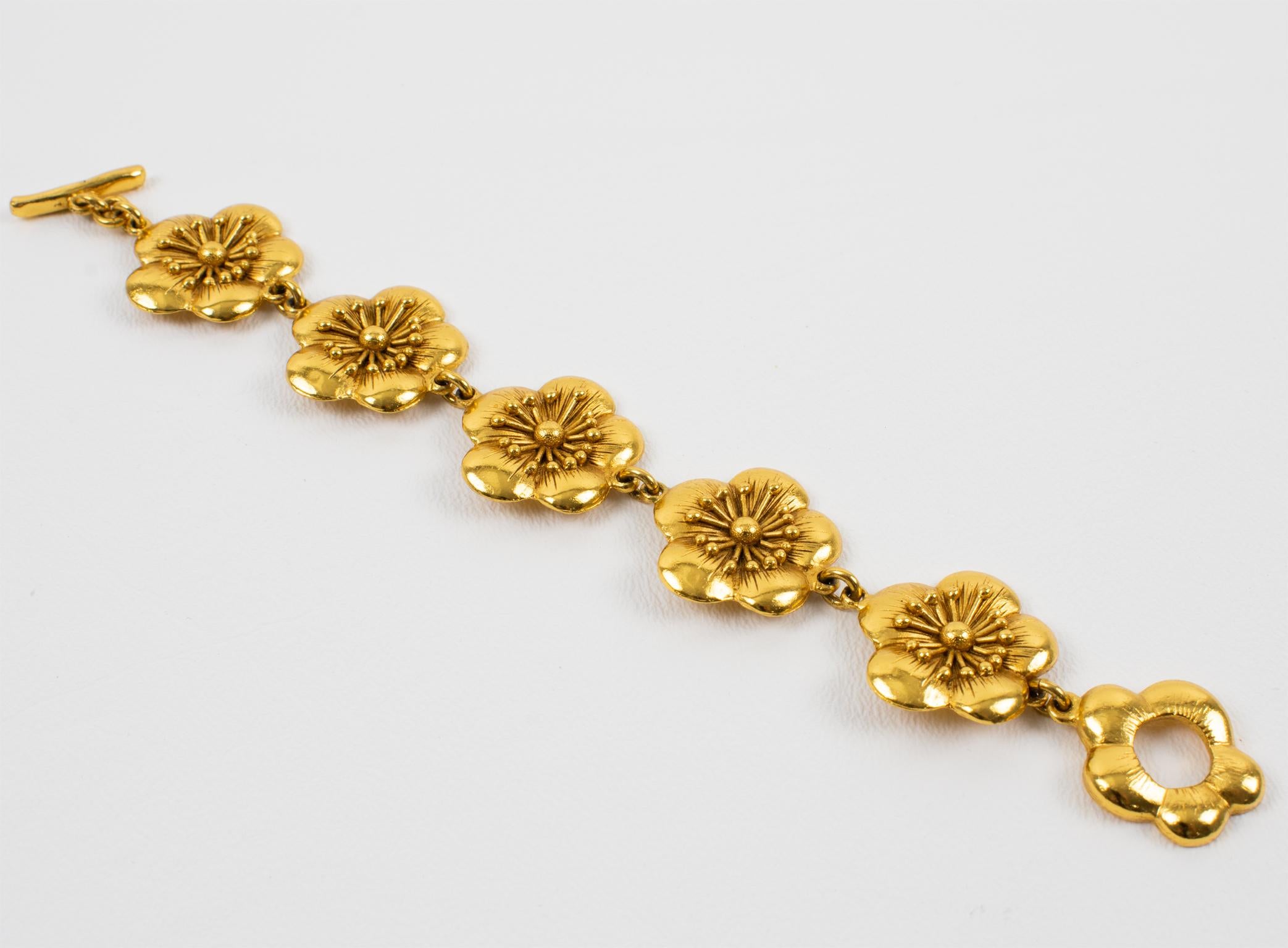 Cet envoûtant bracelet à maillons floraux de Kenzo Paris est en métal doré, tout en fleurs de cerisier sculptées et texturées. Le bracelet se ferme à l'aide d'un fermoir à bascule fleuri. La pièce est marquée en dessous sur la fermeture, et un