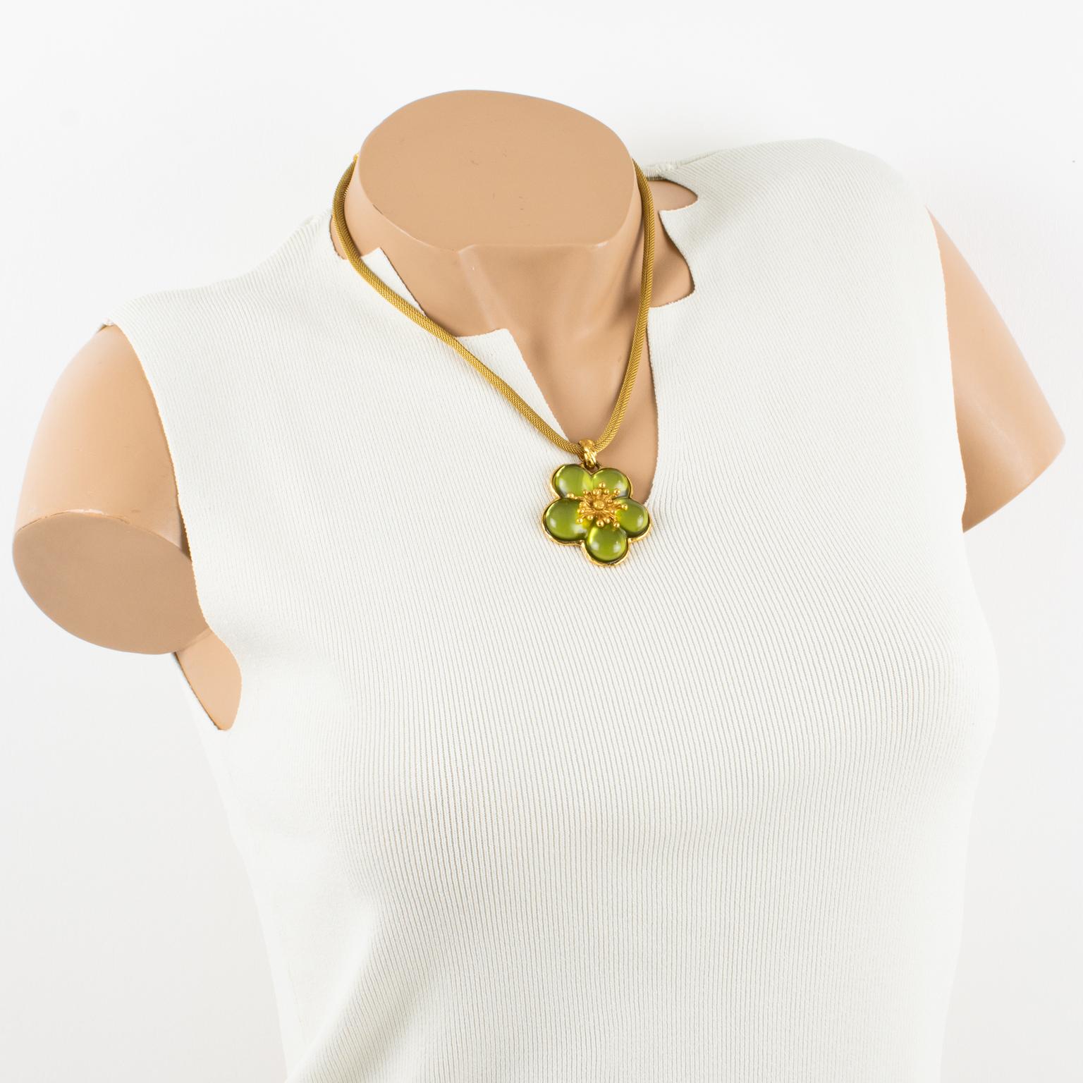 This elegant Kenzo Paris floral pendant necklace features a gilded metal turbogas chain ornate with a cherry blossom design floral pendant. 
The pendant rests on a gold metal frame. It is embellished with avocado green resin. The choker closes with