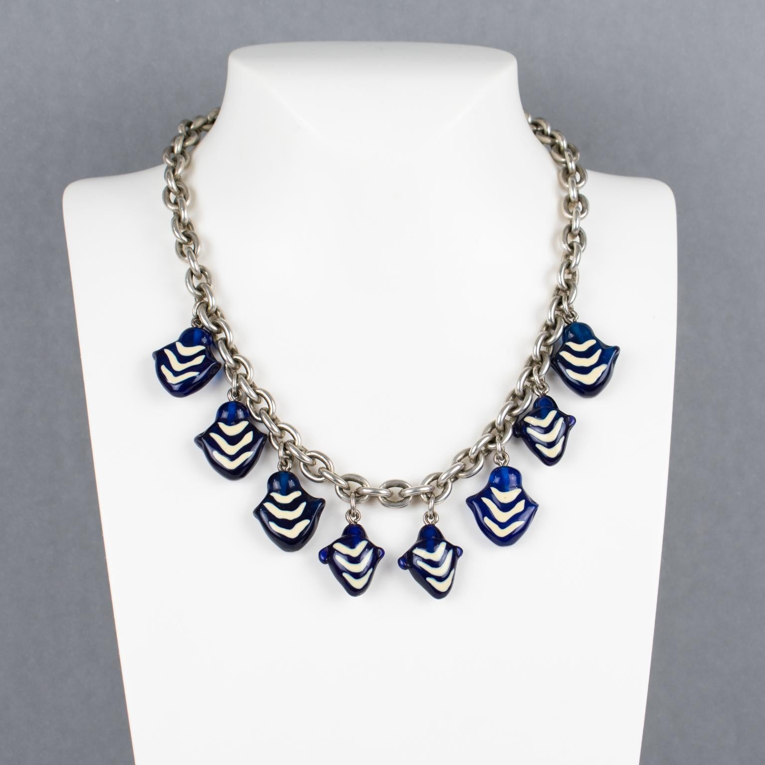 This elegant Kenzo Paris necklace features a heavy silvered metal chain ornate with Murano glass charms. The charm pendants boast a lovely purple-blue color with white contrast embellishments. The choker closes with the classic Kenzo floral