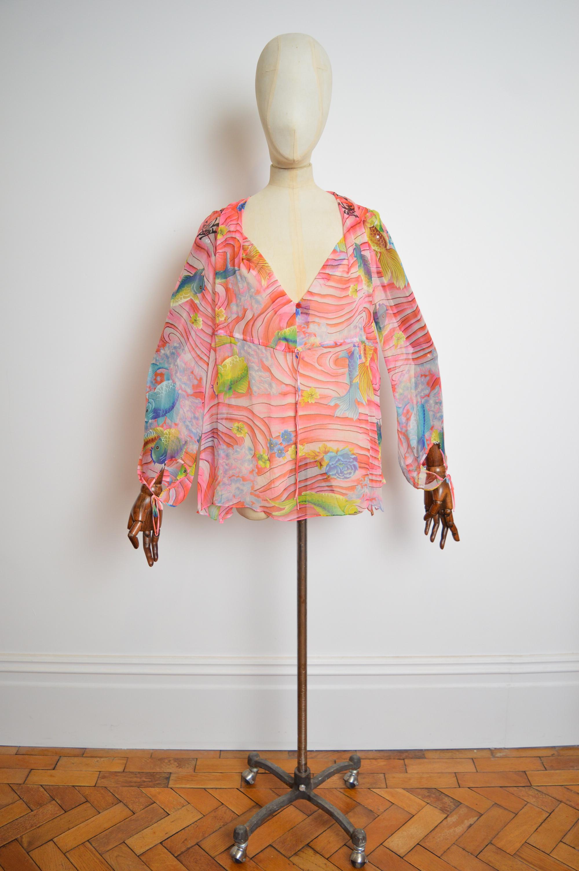  A Beautiful pure silk Japanese Koi Fish patterned pink Sheer Blouse by KENZO.
Adjustable via a draw string tie under the bust to offer multiple silhouettes and fits depending on your desire.
Pit to Pit; up-to 23”
Pit to Cuff; 18”
Nape to Hem;