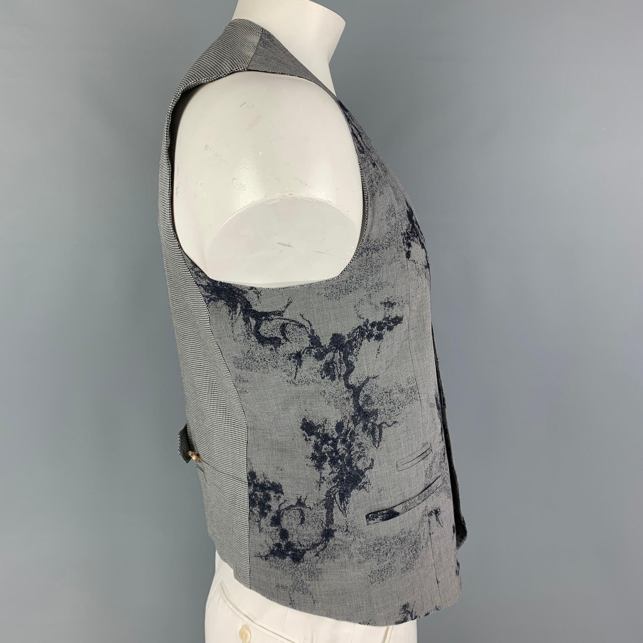 KENZO vest comes in a navy & white cotton blend featuring embroidered designs throughout, slit pockets, side tabs, and a buttoned closure. Made in France.
Good
Pre-Owned Condition. Minor discoloration at front. As-is.  

Marked:   52 

Measurements: