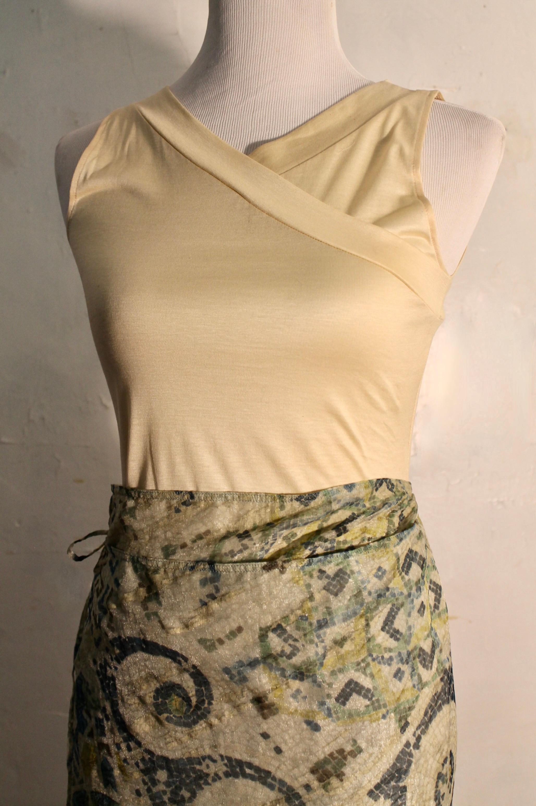 Le devant de la robe se prolonge par un panneau rectangulaire.  À la taille, la jupe devient enveloppante et se noue sur le côté. La doublure de la jupe est en coton. 