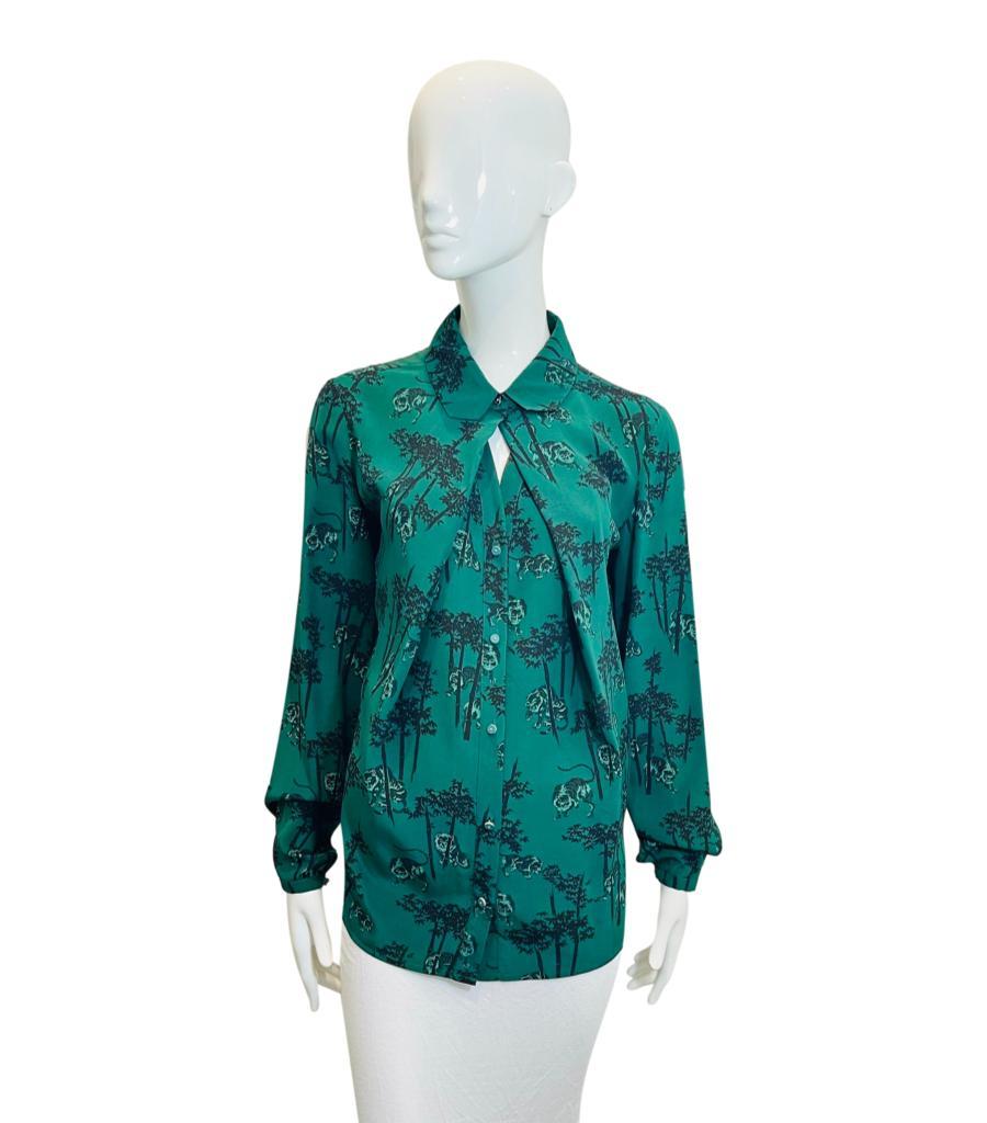 Kenzo Tiger Print Silk Shirt

Emerald green long sleeved shirt designed with the brand's signature 'Tiger' and floral prints in black.

Styled with gathering to the collared neckline creating cut-out detail. Featuring button centre closure, buttoned