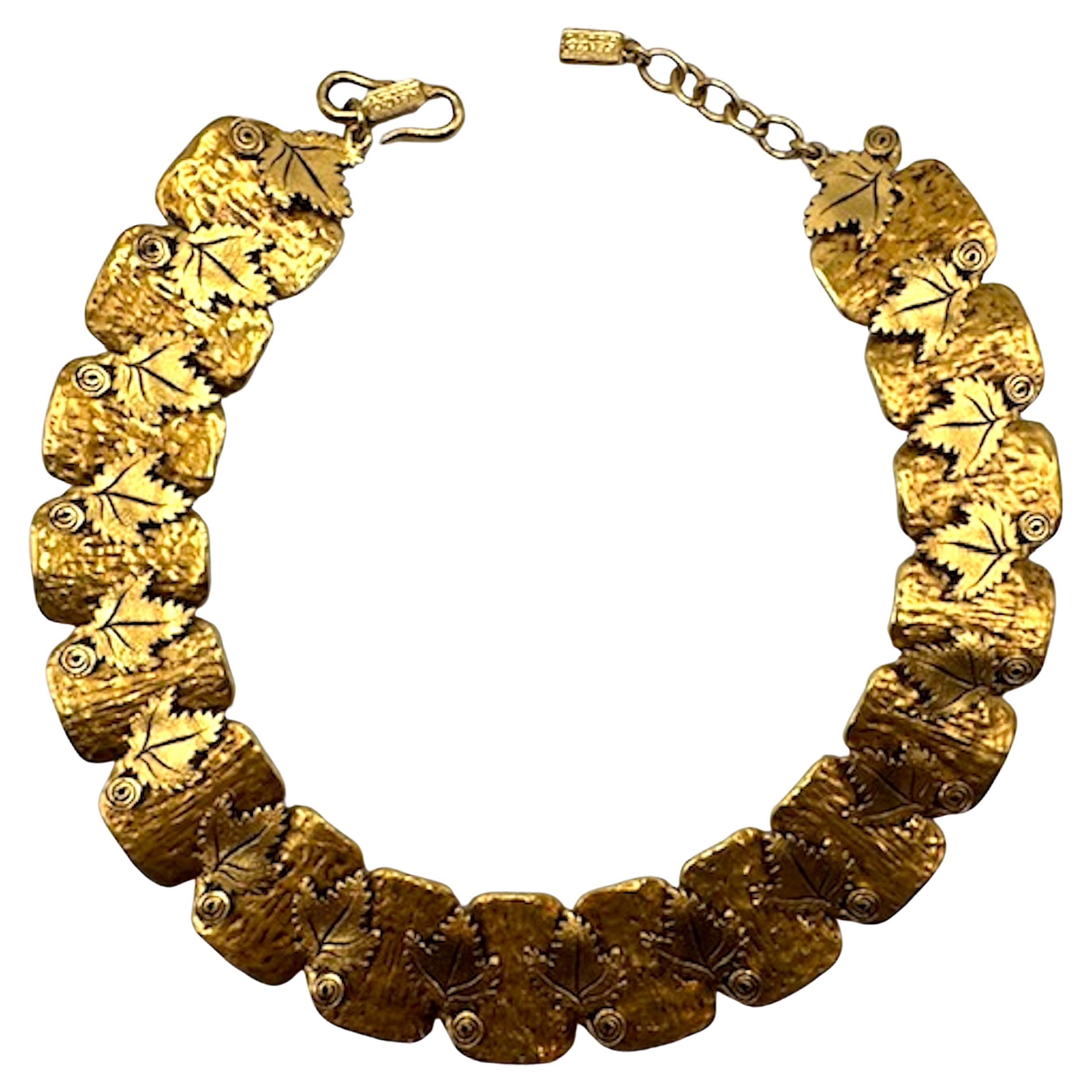 Este llamativo collar vintage de Kenzo captura la atrevida estética inspirada en la naturaleza de los años 80. El diseño presenta 17 placas texturizadas en tono dorado, cada una con un delicado motivo de hojas y acentuadas con un detalle en espiral.