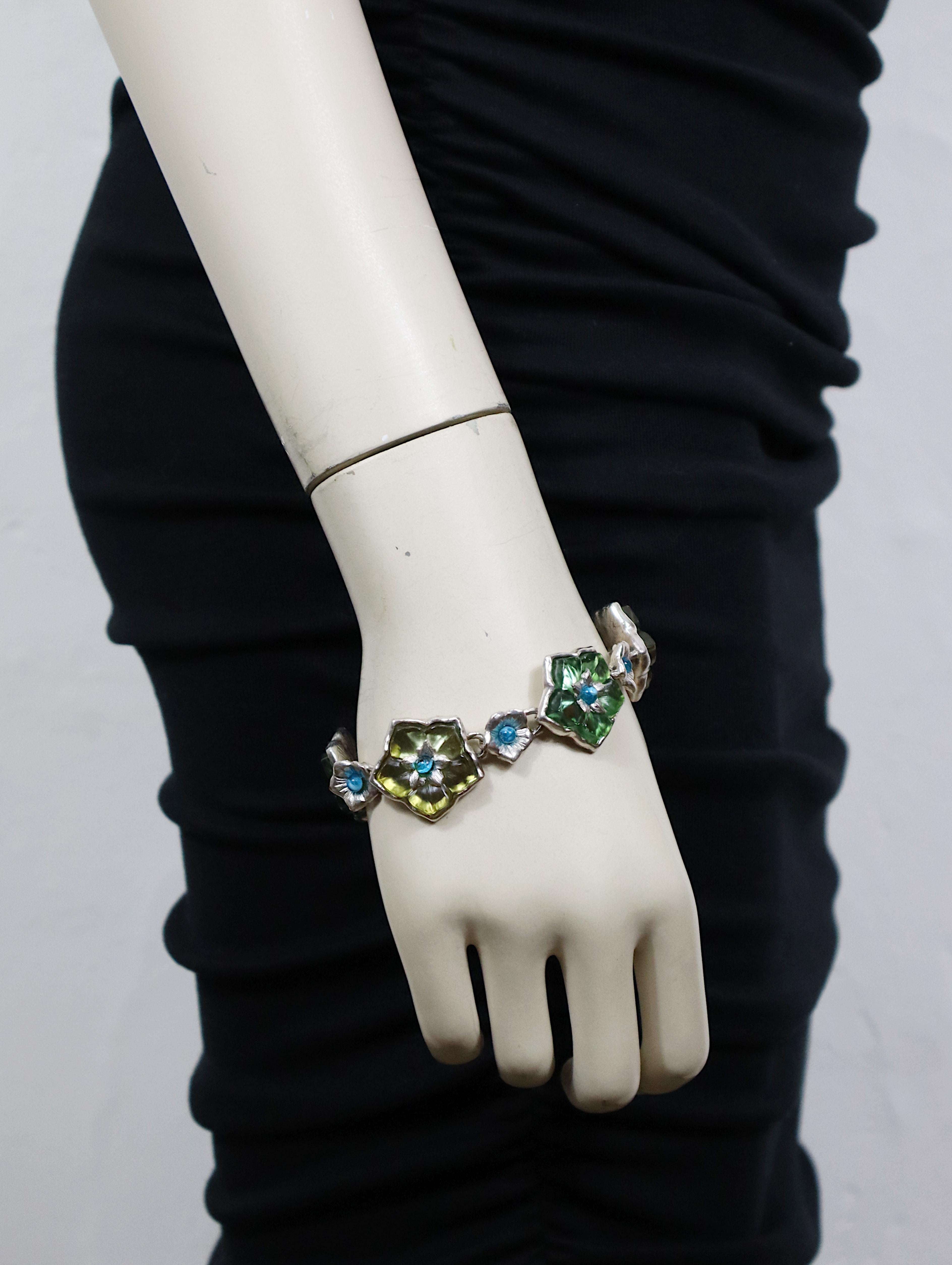 KENZO vintage silver tone floral bracelet featuring resin flower links embellished with a blue glass cabochon at the center.

Hook clasp closure.

Embossed KENZO Paris.

Indicative measurements : adjustable length from approx. 19.5 cm (7.68 inches)