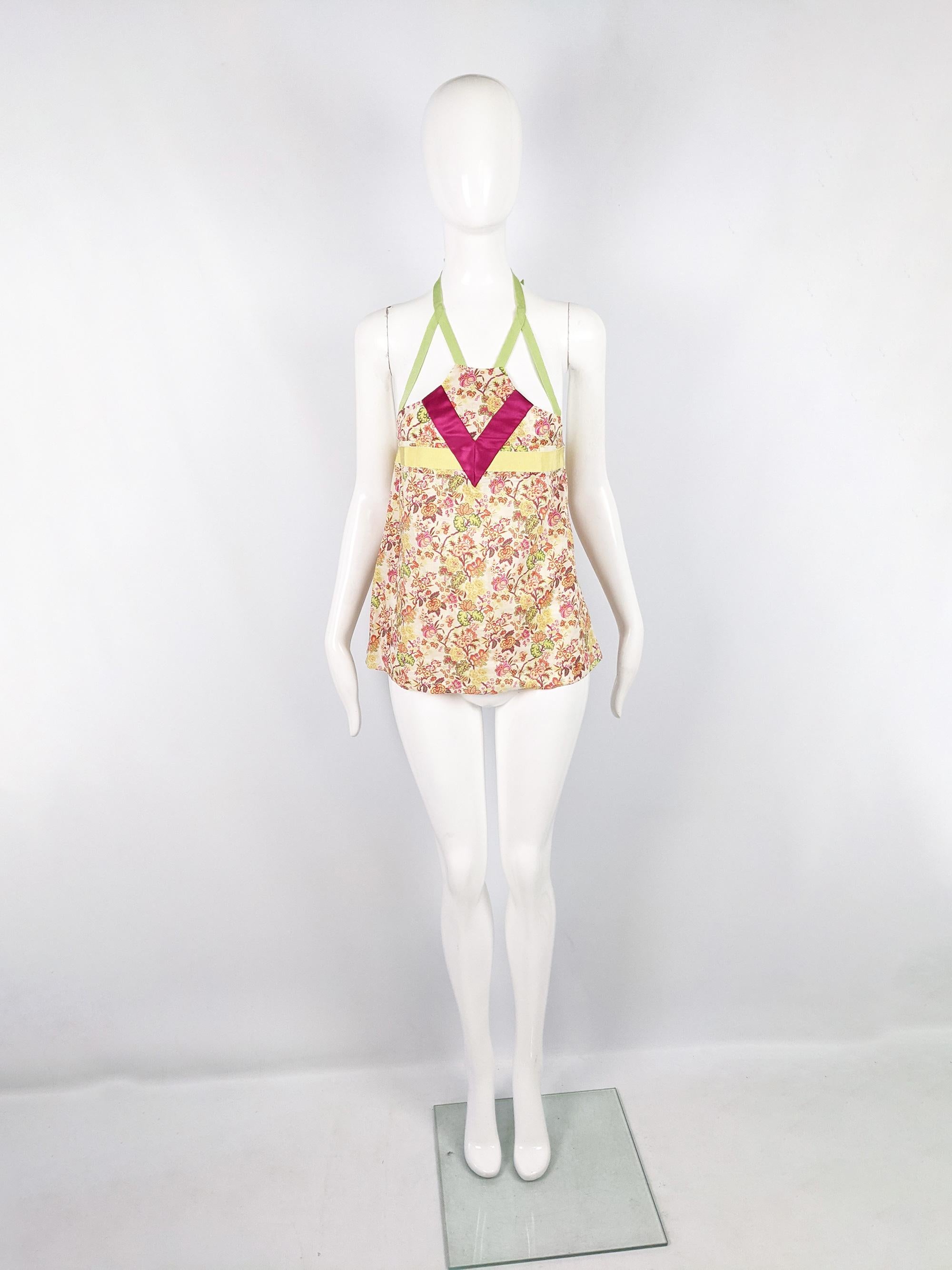 A super cute y2k vintage Kenzo top from the early 2000s. In a floral print cotton with pink and yellow satin panels across and a green grosgrain halter neck tie that ties around the back of the neck. With a cut that flares outwards from the bust.