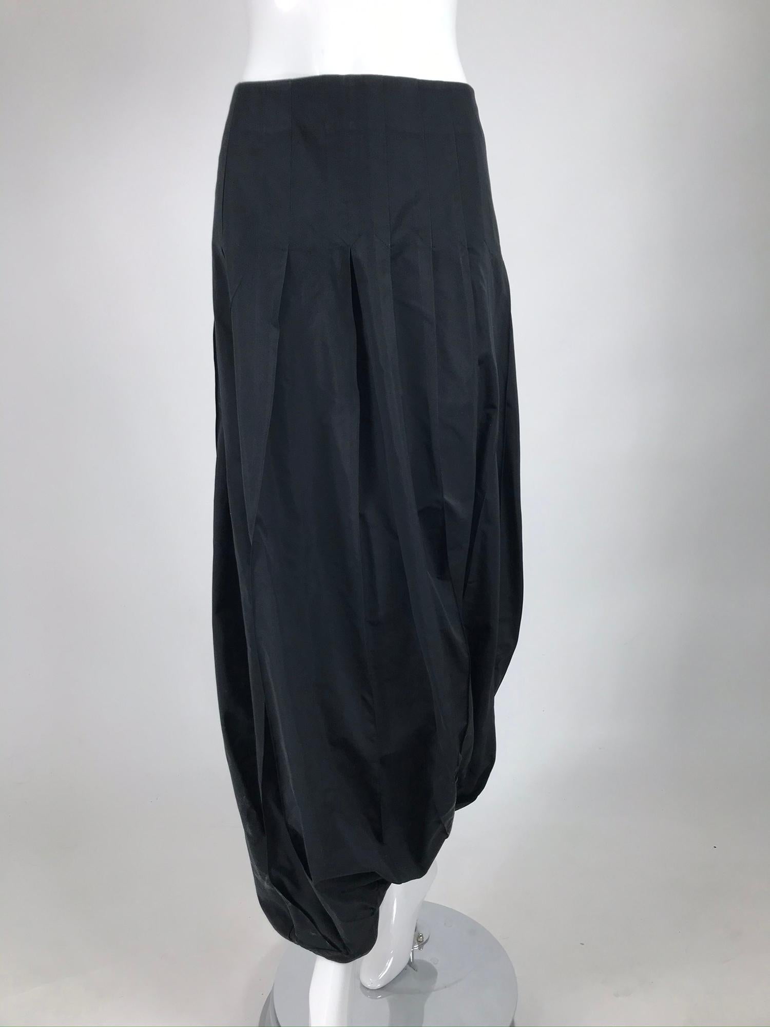 Kenzo zouave trouser in black taffeta from the late 1980s. Matte black taffeta trouser/skirt is fitted through the waist to the hip via inverted pleats that open full to the hem. The skirt is gathered at the hem into a horizontal center band,