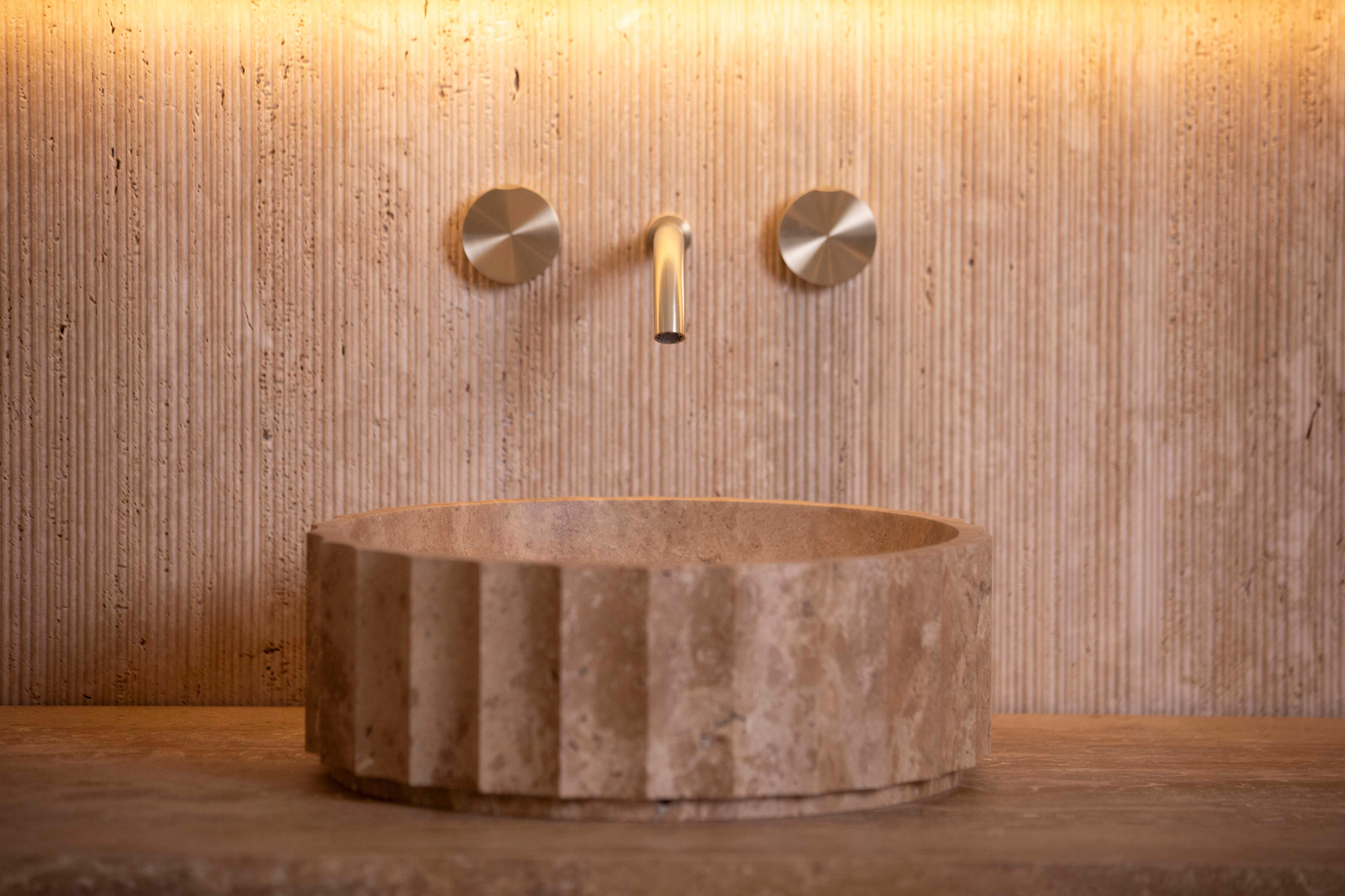 The Kepi travertine countertop washbasin by Piba Marmi is a stunning expression of timeless design and artisanal craftsmanship. Its vertical concave grooves evoke the elegance of the Art Deco era, blending geometric precision with a sense of warmth