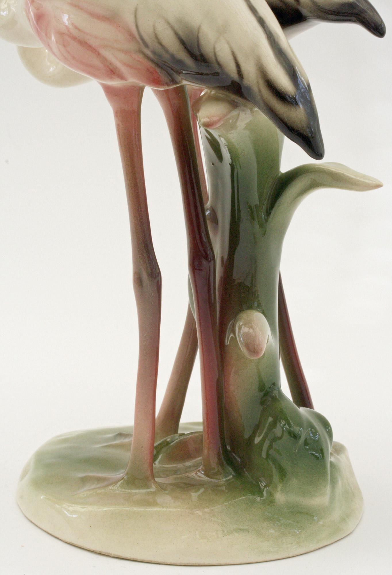 A fine pair Austrian Art Deco hand painted pottery figures of flamingos by Keramos of Wien and dating between 1920 and 1930. The figure comprises of two flamingo’s standing side by side on a rounded moulded base with a tall shrub growing to one