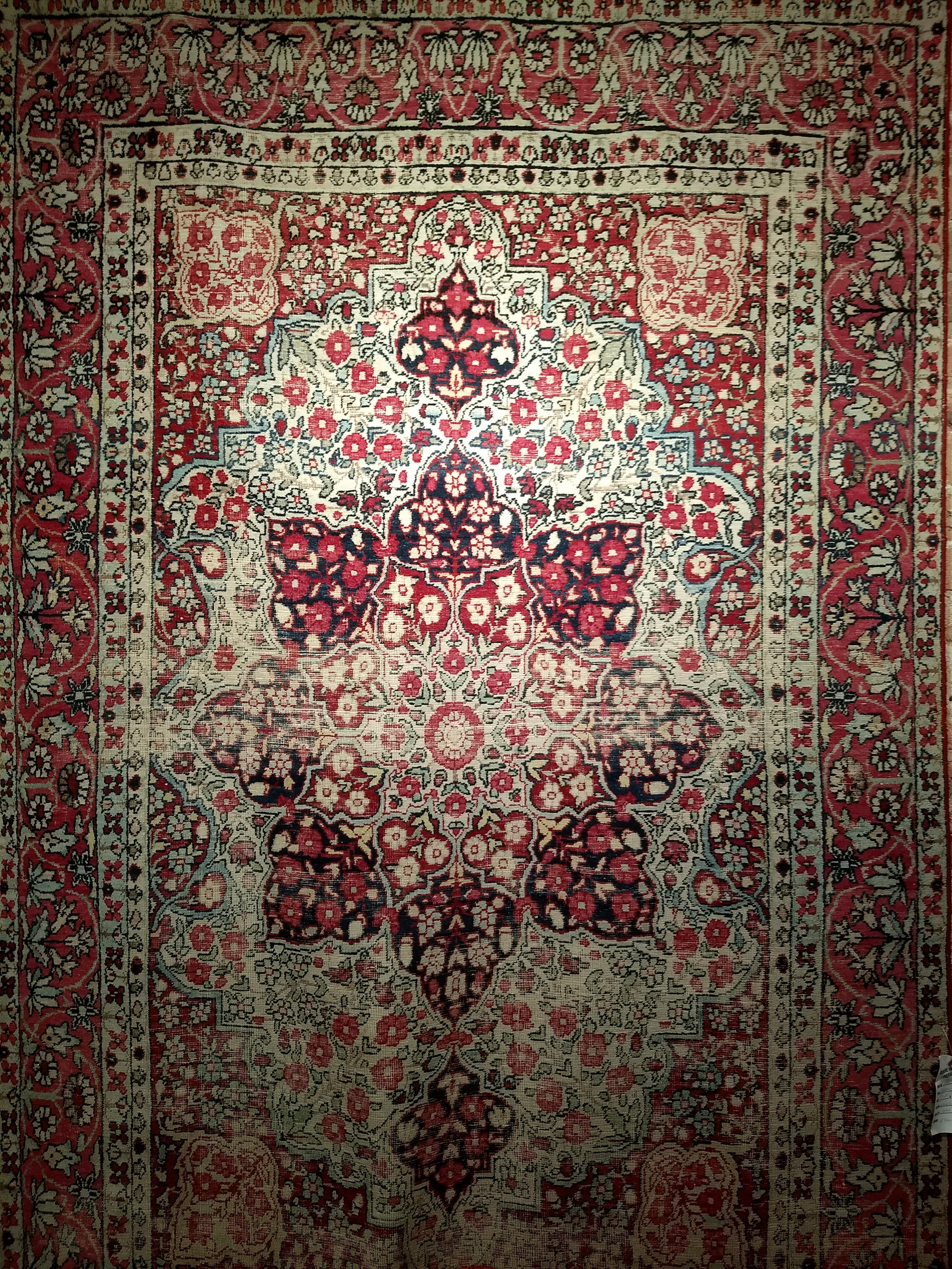 Un magnifique tapis Kerman Lavar de la fin des années 1800. Le champ principal est de couleur ivoire, les écoinçons d'angle sont rouges et la bordure est rouge rosé. Le tapis présente un motif floral dans les tons rouge, bleu clair et crème. La