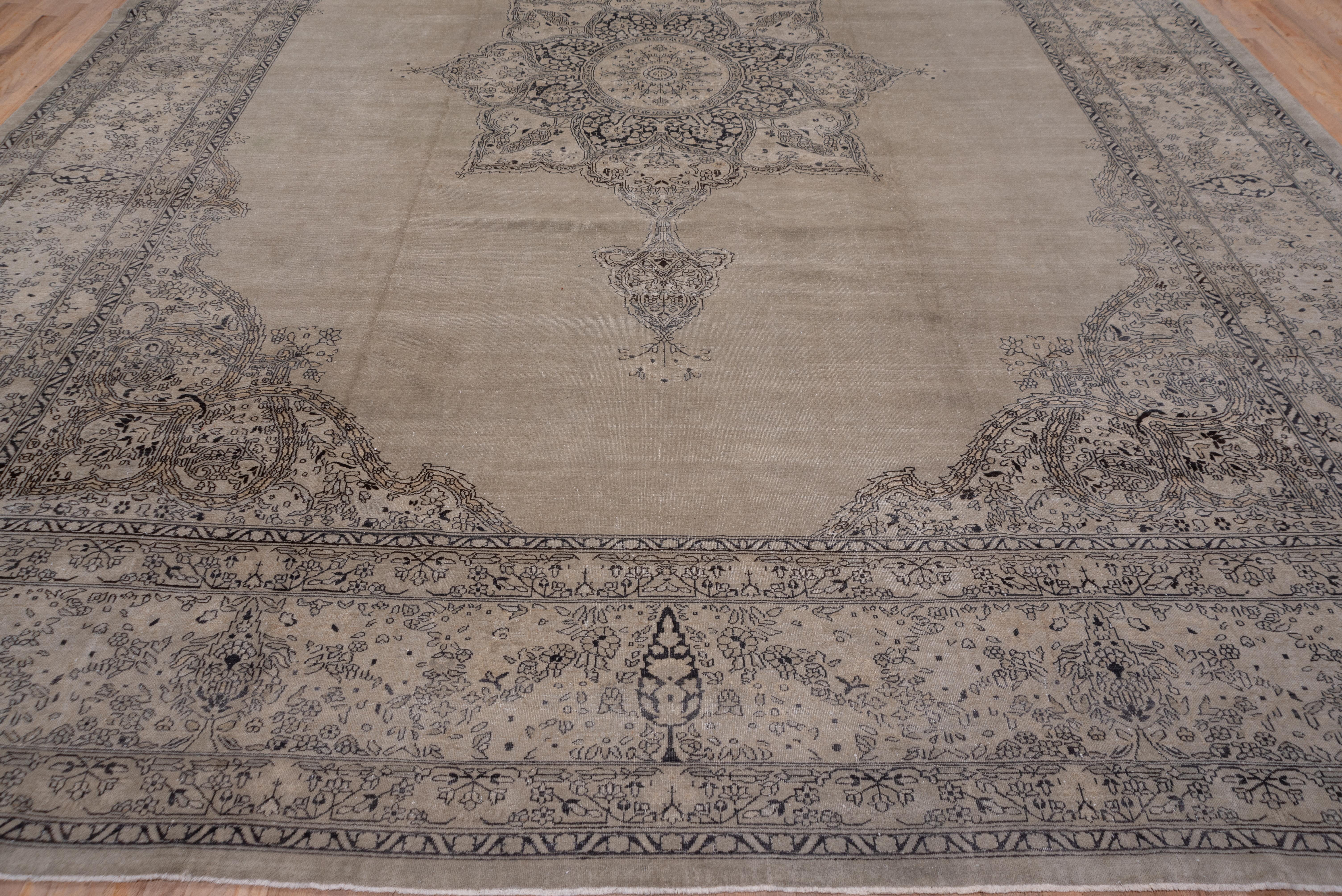 In the Persian Kerman manner with a large pendant octogramed medallion and circular sub-medallion on the open beige field with split arabesque scrolling corners. The Kerman theme continues in the main border with its cypress tree and flower spray
