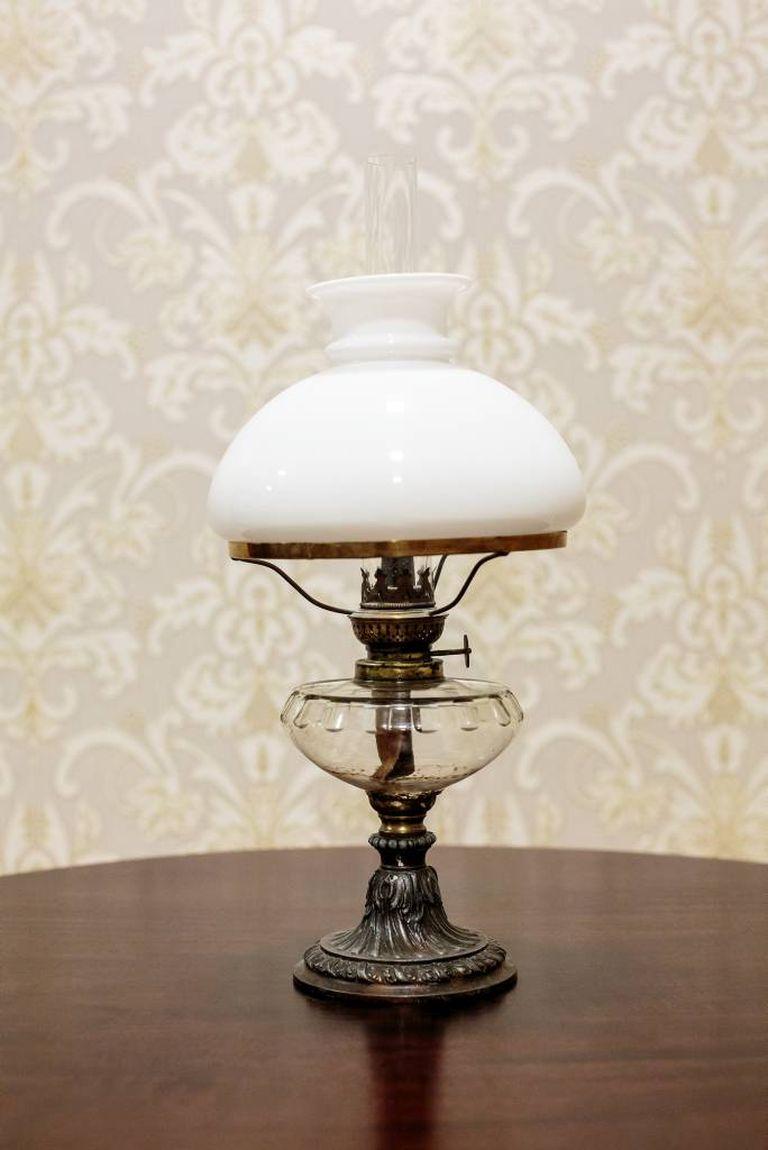 The lamp stands on a tin foot, and has a glass kerosene container.
The lampshade is made of milky glass.

Measure: Height 49 cm.

The lampshade diameter: 22 cm.

The lamp functional, in very good condition.