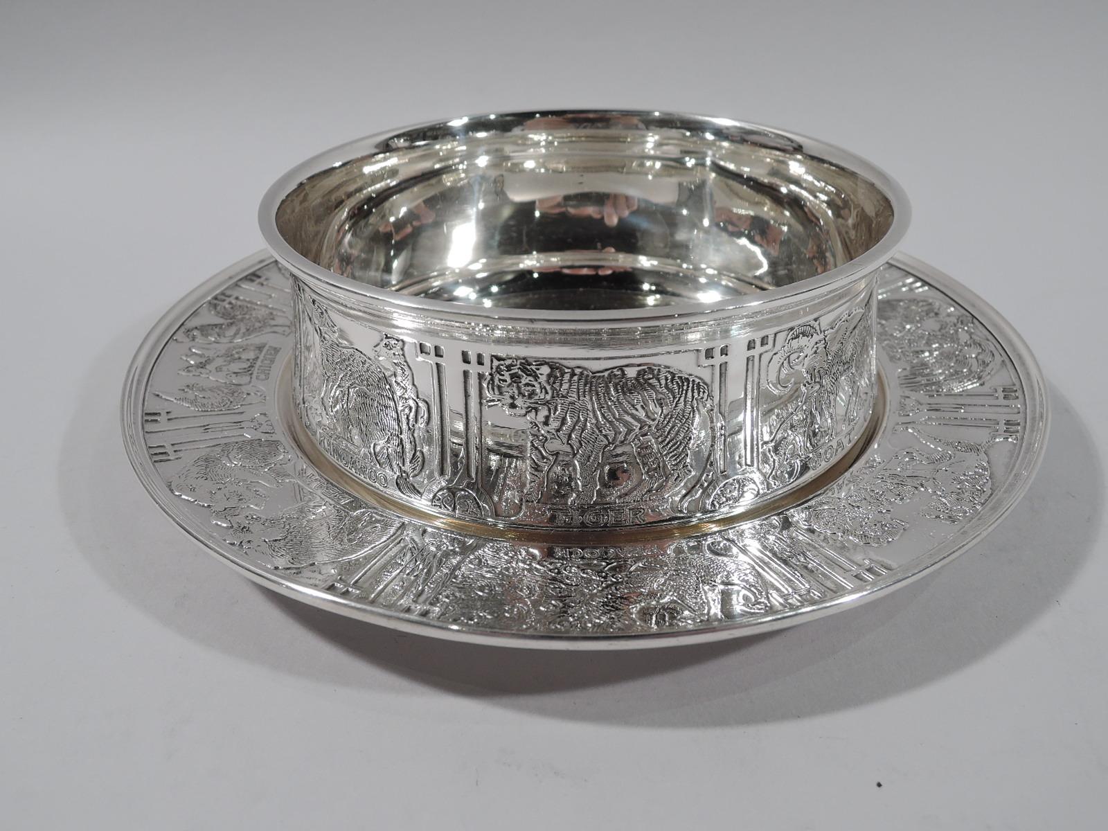 Edwardian sterling silver baby bowl on plate. Made by Kerr in Newark. Bowl has gently upward tapering sides and plain flat rim. Plate has deep plain well. Acid-etched menagerie with lions and tigers and bears as well as domestic critters like cats