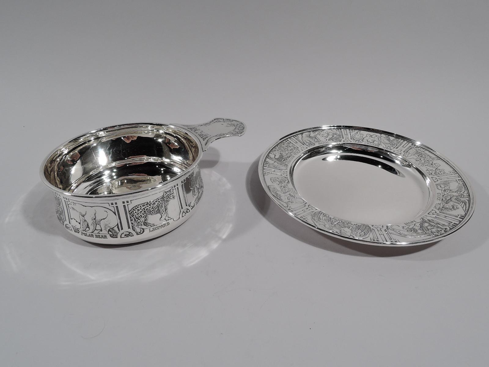 Edwardian sterling silver baby porringer on plate. Made by Kerr in Newark, circa 1915. Porringer has gently upward tapering sides and solid shaped handle. Plate has deep plain well. Acid-etched menagerie with lions and tigers and bears as well as