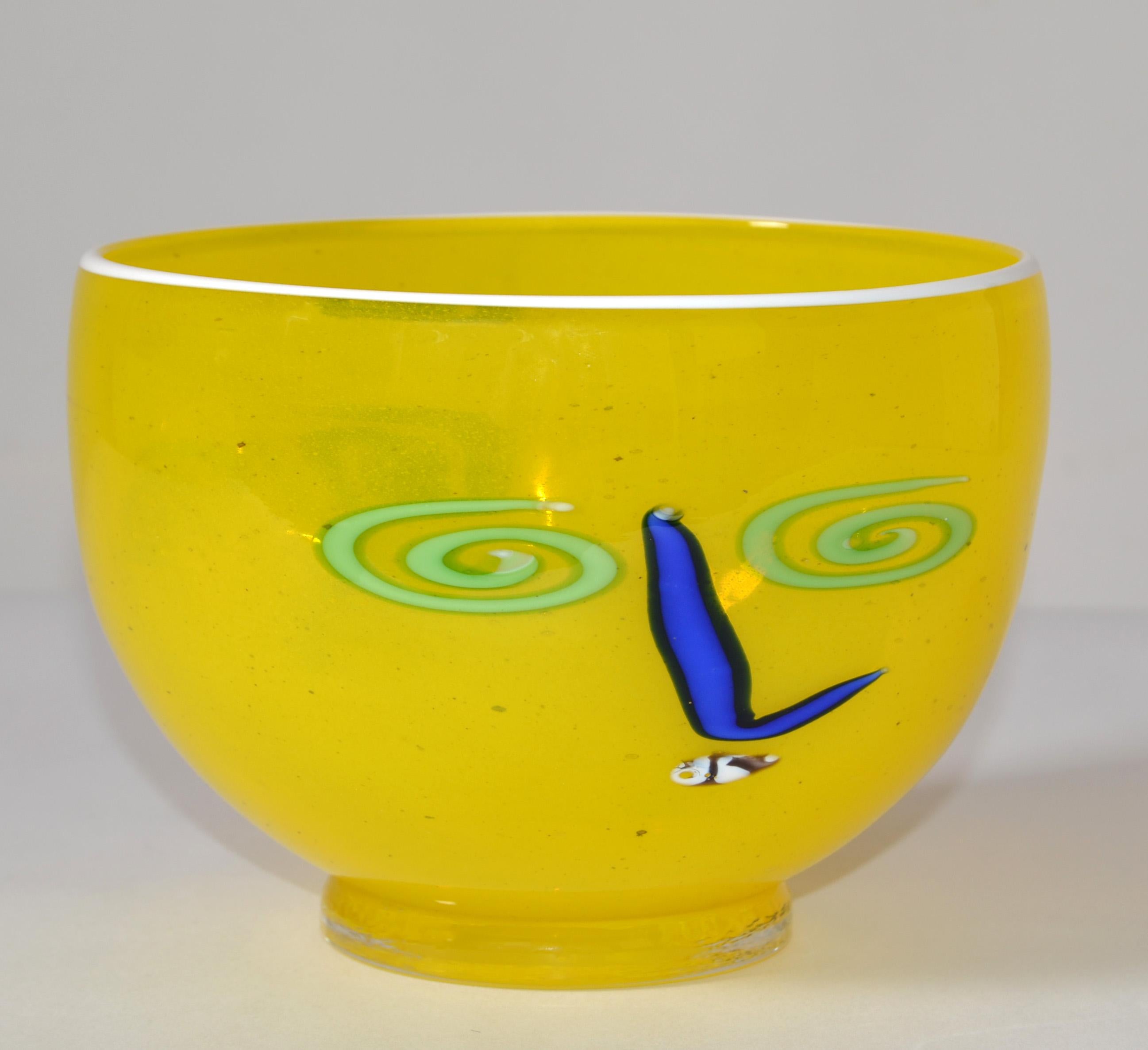 Mid-Century Modern Op Art Glass Bowl styled after Picasso by Artist Kerry Feldman for Fine line.
Canary Yellow Bowl depicting blue abstract eyes and a pink abstract Nose. The Top edge is in white milk glass decor.
Signature by the Artist at the