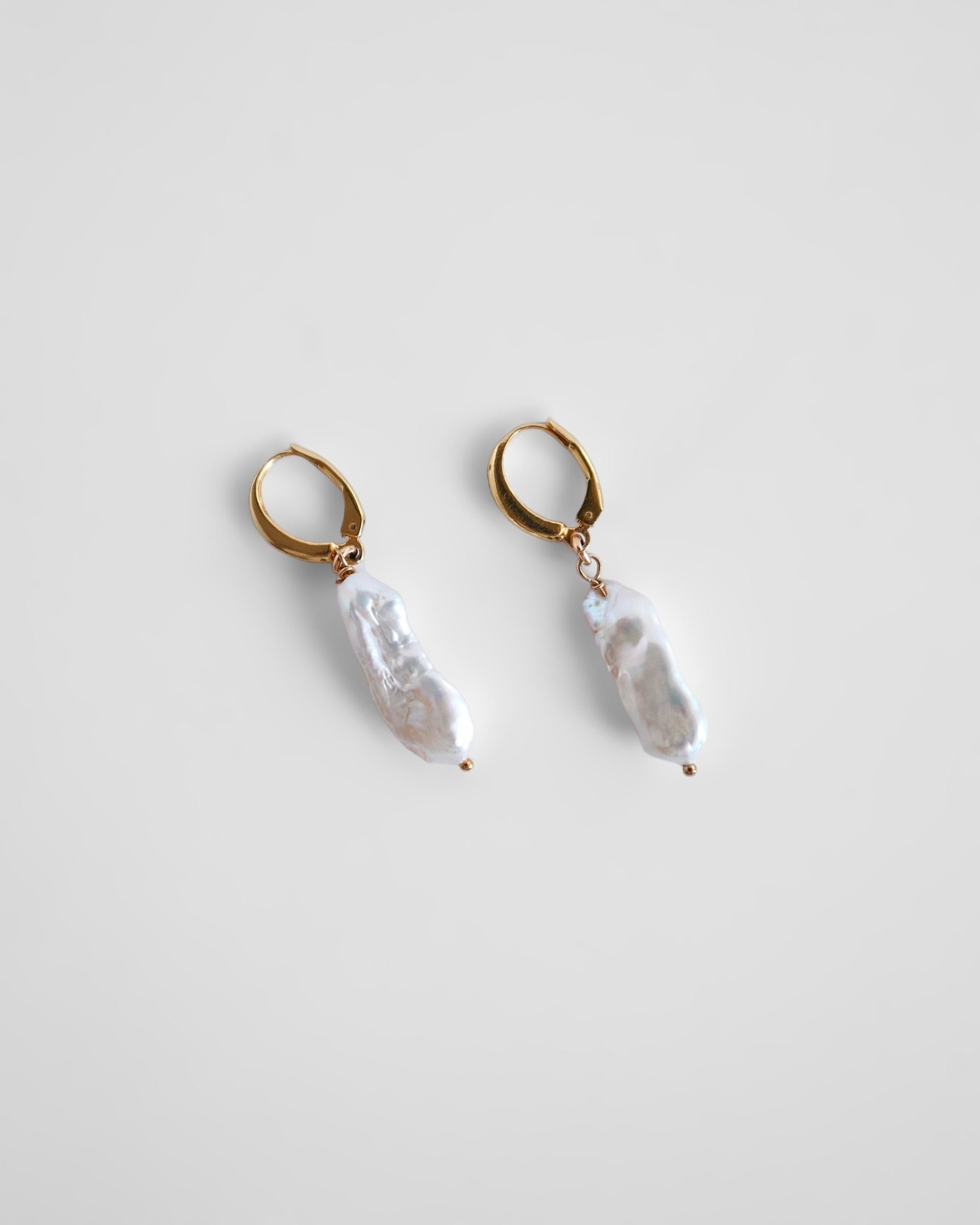 Elevate your look with our modern take on pearls. The Gaia earrings exude subtle elegance.

Ships within 2 weeks 

4 month warranty

Details:
- 40mm long approximately
- 14K gold filled lever back hooks
- Freshwater Keshi pearls 20mm height