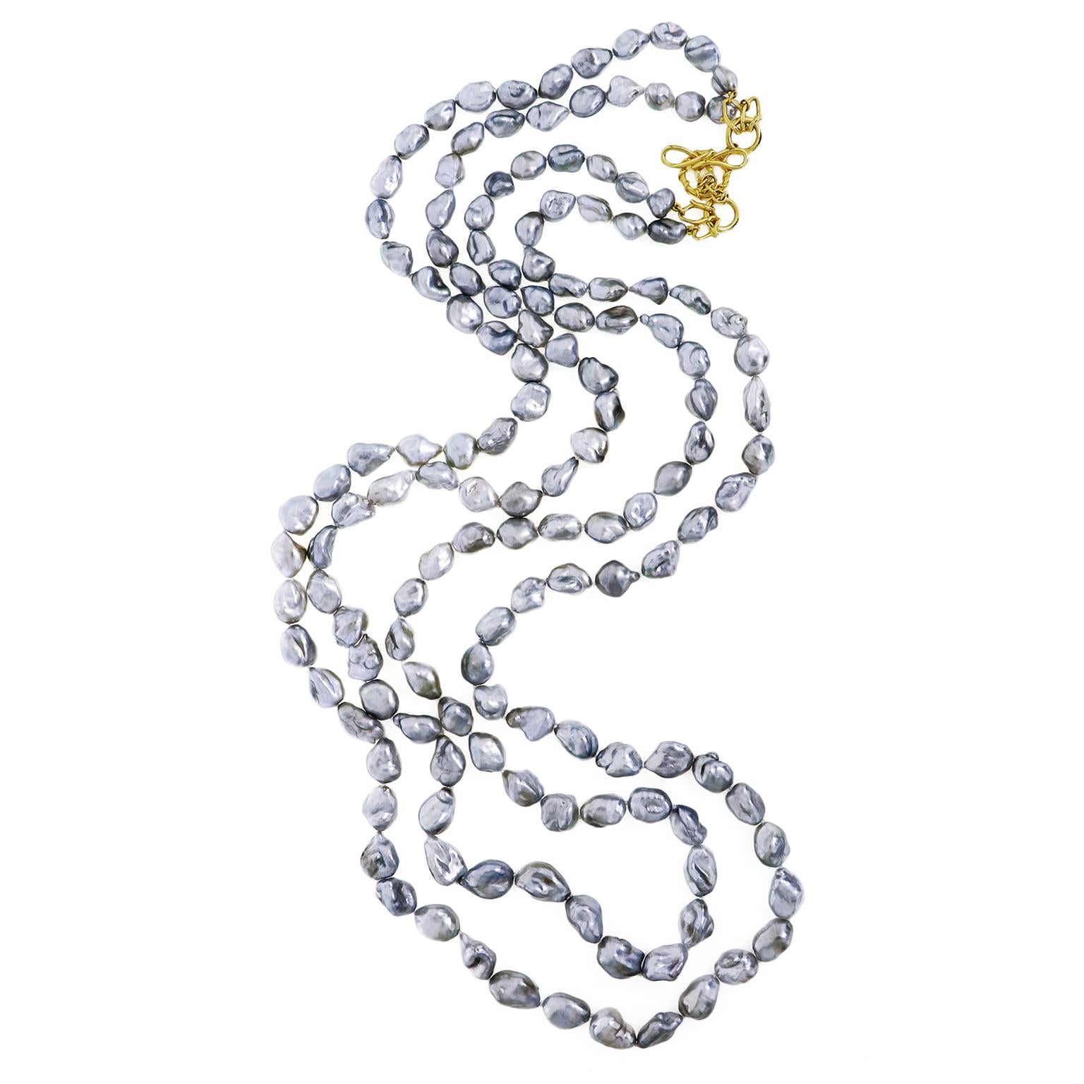 Showcasing the grey keshi pearl, 2 strands of this baroque shaped gemstone are arranged largest in the middle and descend in size towards the ends. Light catches these nacre pearls, which allows them to radiate. 18k yellow gold Vs unify the two