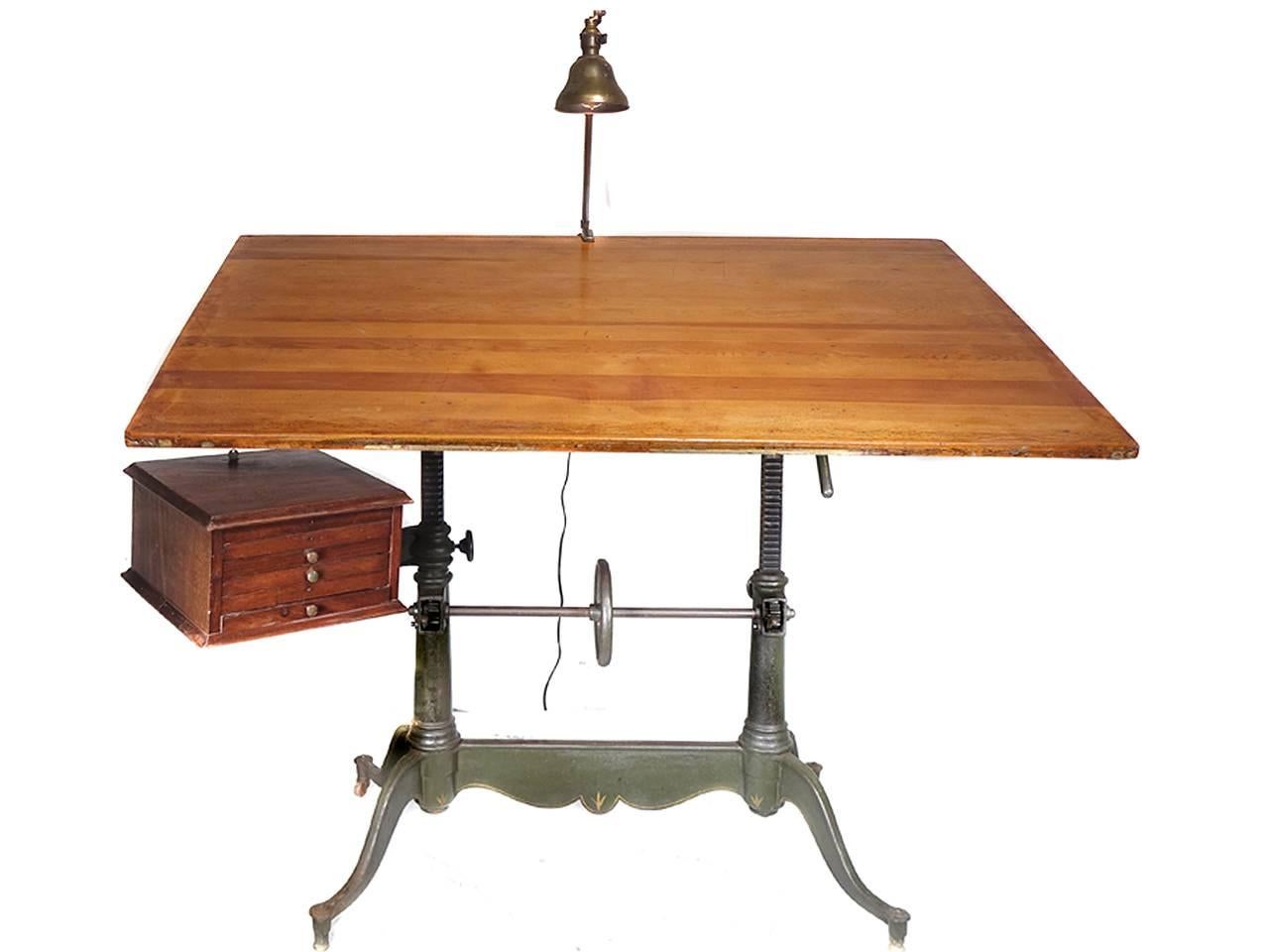 This is an exceptional antique cast iron double pedestal drafting table by Keuffel & Esser, with a beautiful detailed base having a centre wheel for height adjustment, and a locking mechanism for tilt adjustment. This handsome table also has the