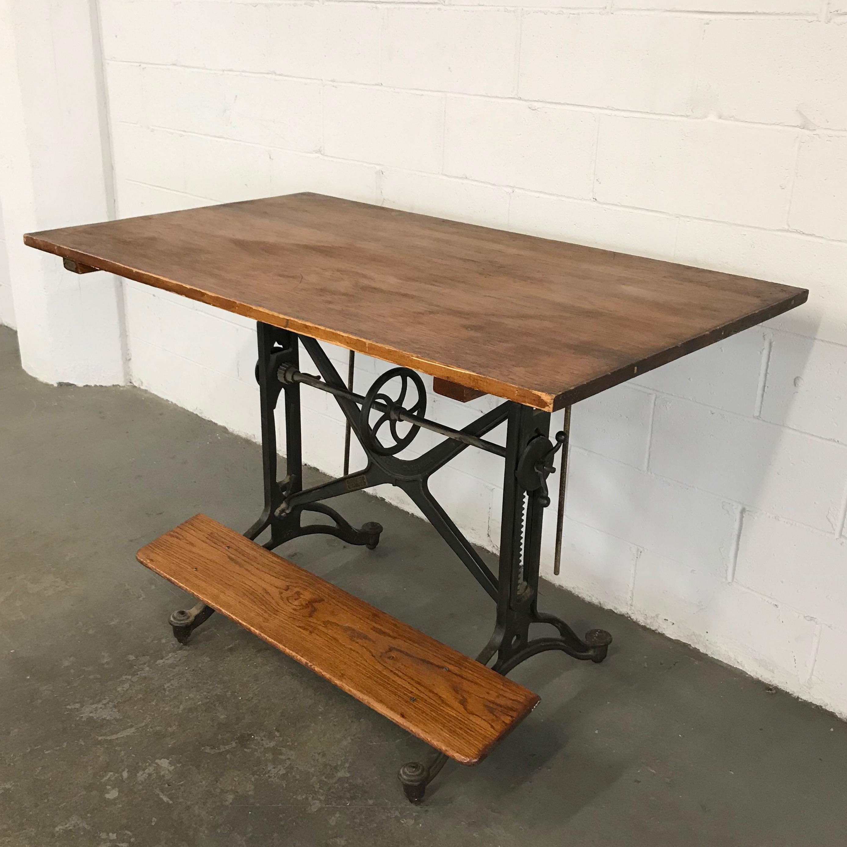 Early 20th century, drafting table model #16535 by Keuffel & Esser Co features a height and tilt adjustable, cast iron base with pine top and oak foot rest. The table is tilt adjustable and height is adjustable from 37.5 inches to 48 inches.