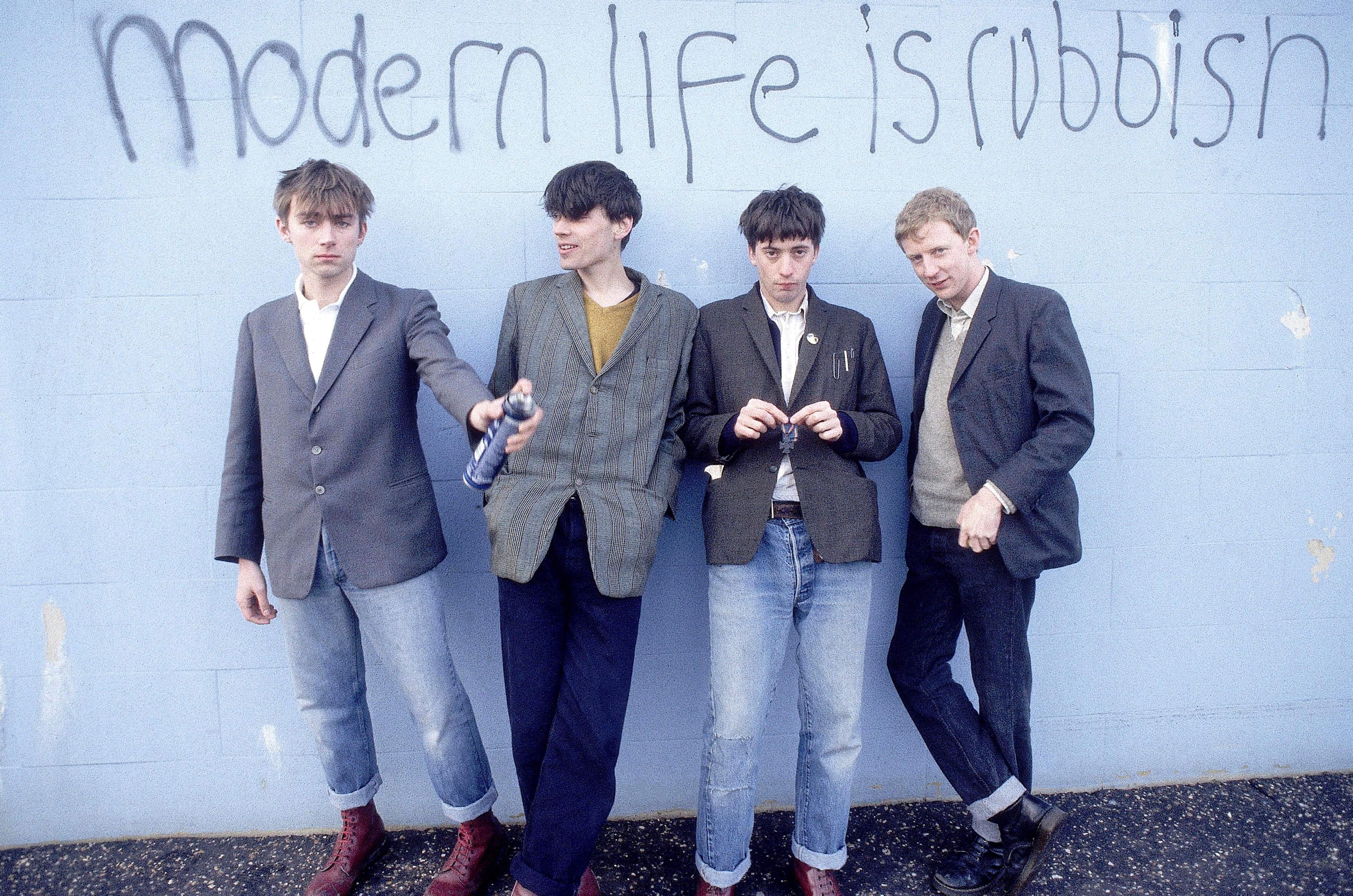 Tirage en édition limitée signé du groupe anglais Blur, posant devant le slogan graffiti "Modern Life is Rubbish", le titre de leur album de 1993. Les Blur étaient les rois de la Britpop et sont de gauche à droite : Damon Albarn, Alex James, Graham