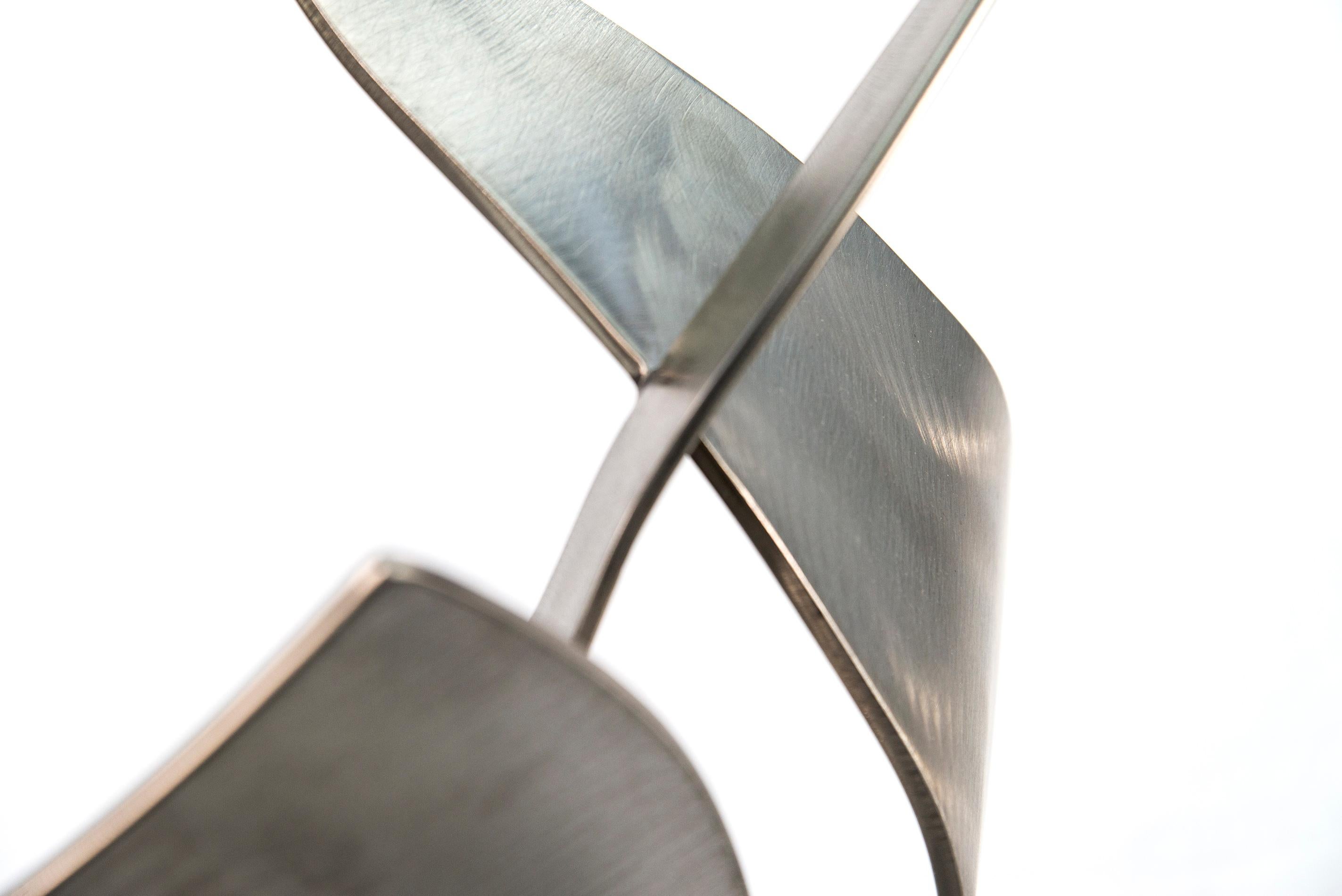 They appear to dance in mid-air. This is Kevin Robb. His graceful, curved abstract sculptures are hand forged from stainless steel. The highly polished surfaces of the three intersecting pieces reflect light and cast shadows. Working as a sculptor
