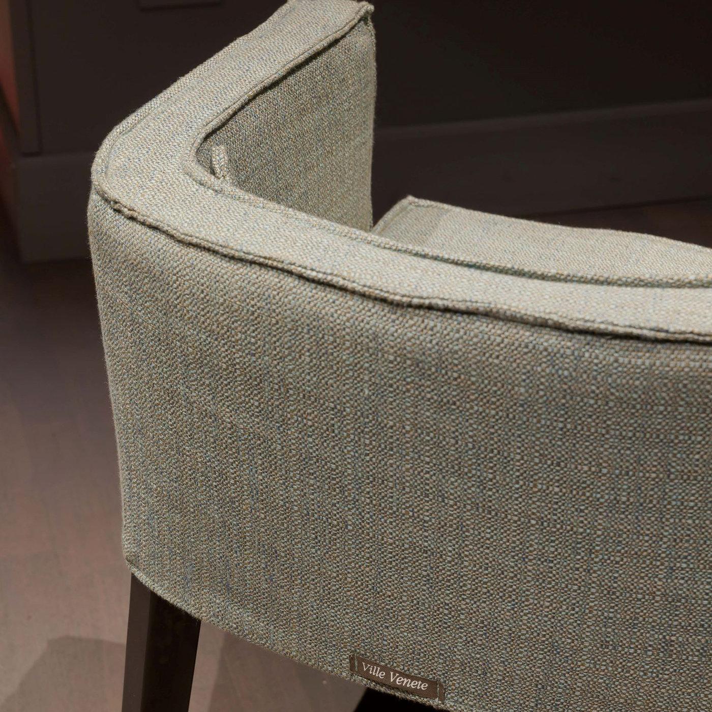 Perfect in residential or commercial contexts alike alongside a coffee table, this armchair is sure to impress. The sturdy wooden frame features a U-shaped backrest/armrests wholly upholstered in a textured gray fabric also used as a cover for the