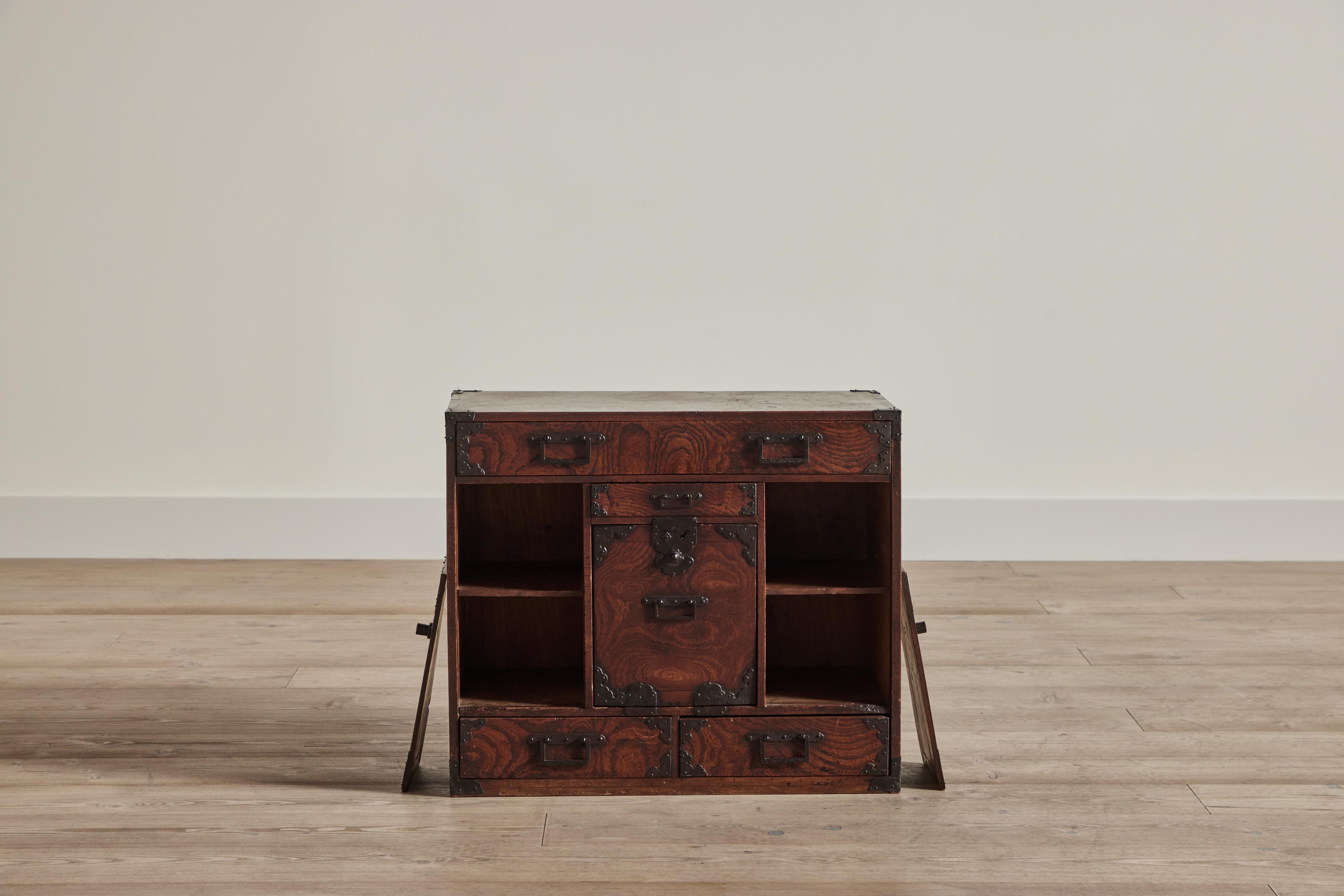 Late 19th century tansu chest from Japan made of Keyaki wood and iron hardware. Chest has multiple drawers and compartments behind three wood doors. 