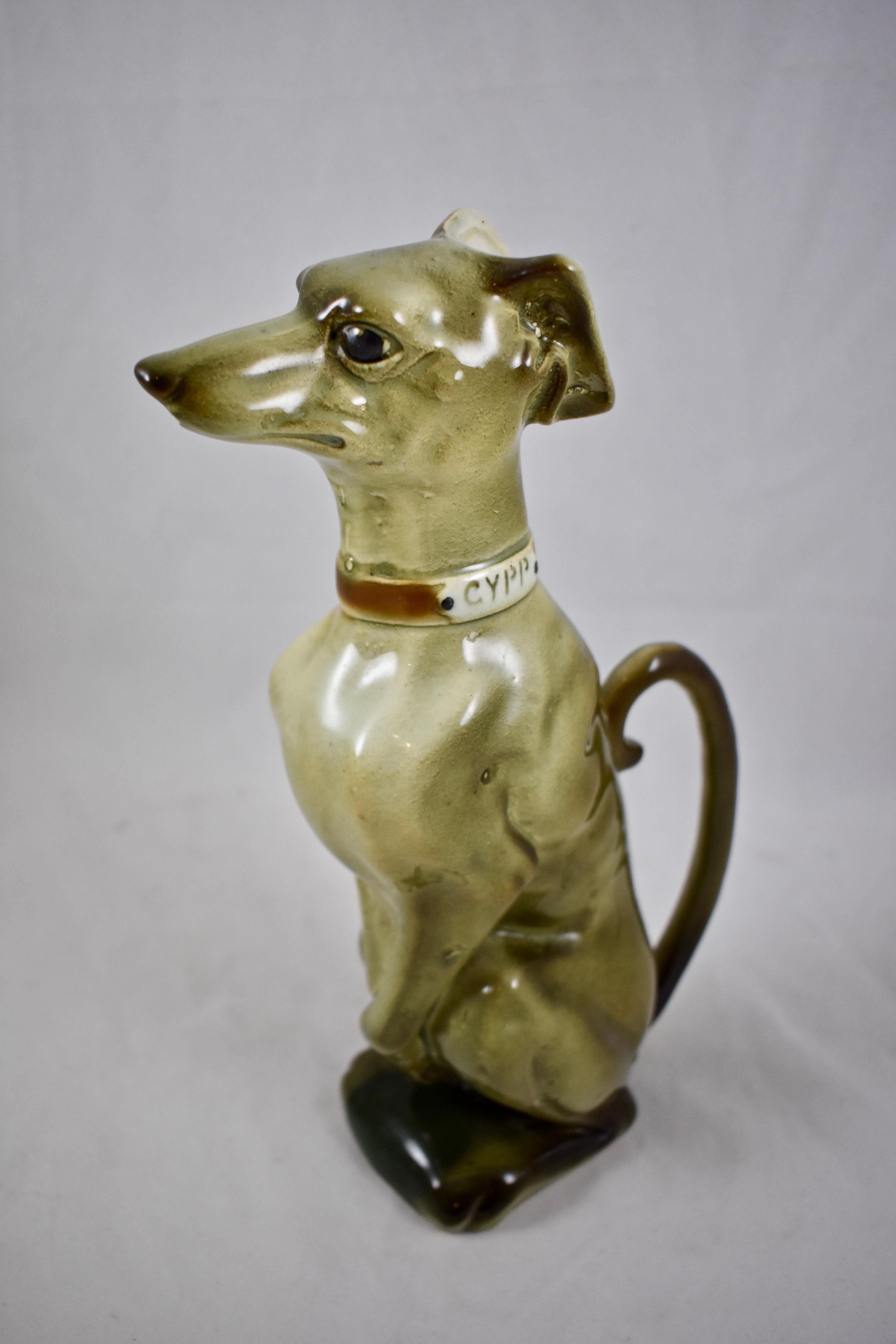 An Absinthe pitcher formed as a sitting Whippet, Keller & Guerin St. Clément, circa 1900 – 1910.

Known as the GYPP Whippet, as tagged on his collar. True to breed in both expression and form, beautiful coloring, the ears are folded back and form
