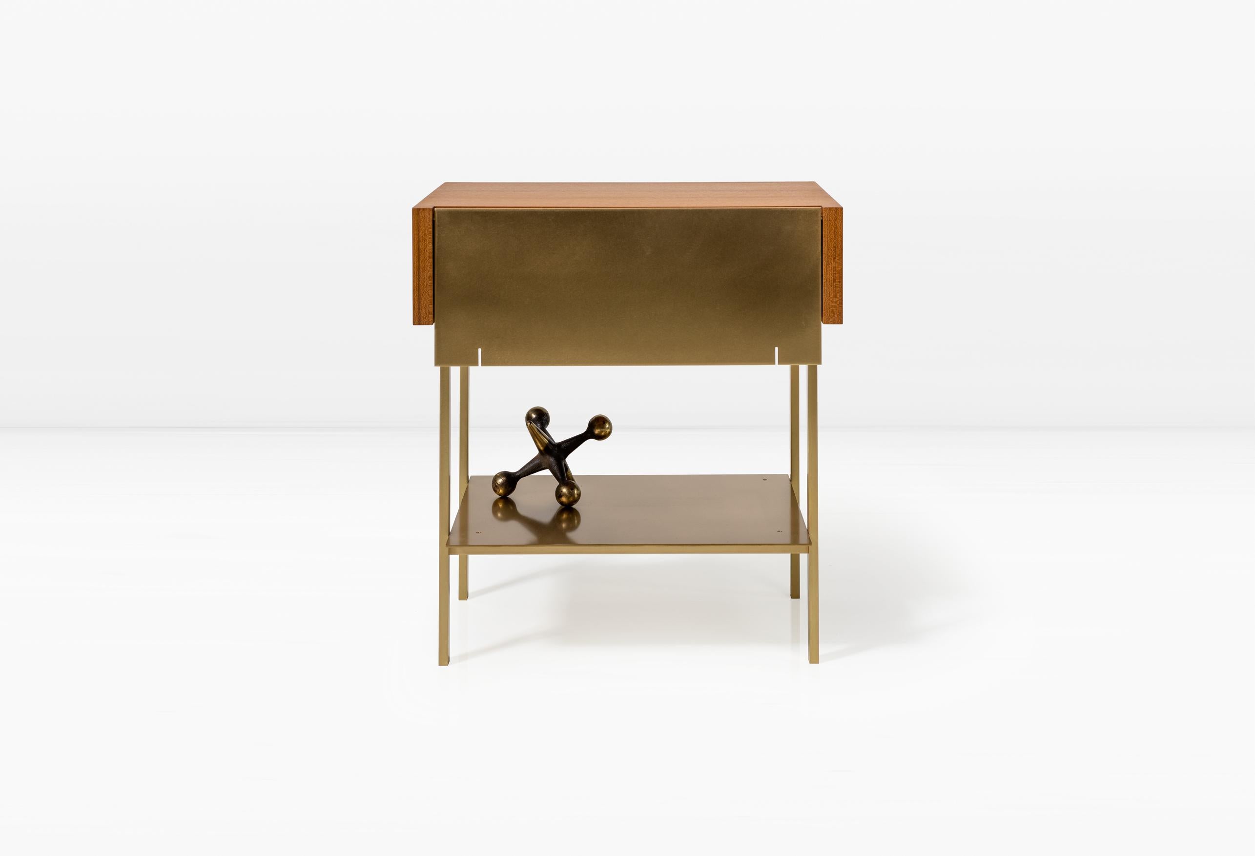 In a juxtaposition of two- and three-dimensional forms, the Hearns End Table combines planes of solid brass with a wooden volume. The drawer is accessed via a recess in the wood to eliminate the need for a pull.

This is a natural product that may