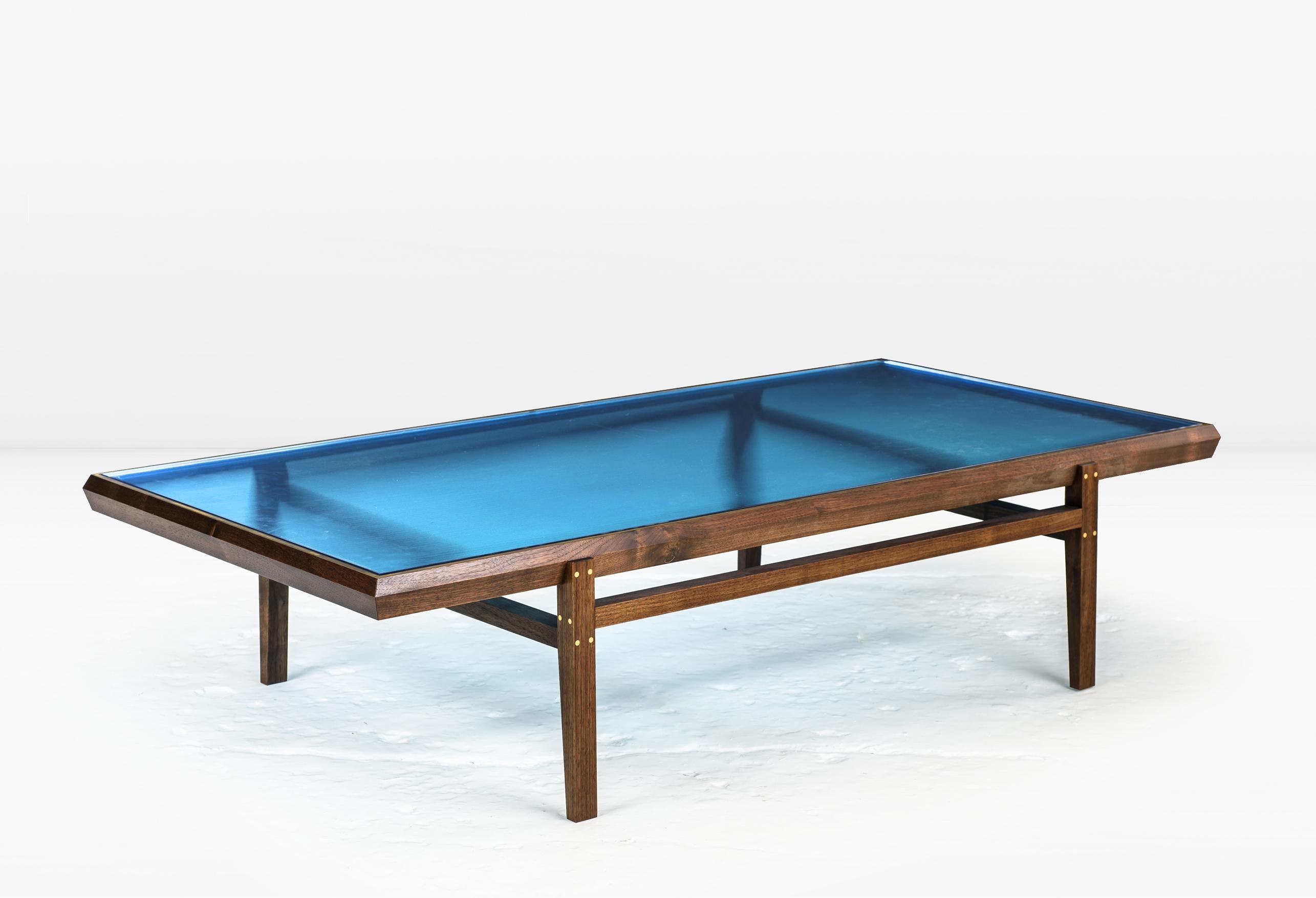 The Pintor Coffee Table’s solid wood frame with Brass inlay is engineered with chamfered edges to provide a simple but worthy setting for the jewel toned, colored glass which forms the tabletop. 

Shown with a solid American Black Walnut frame and