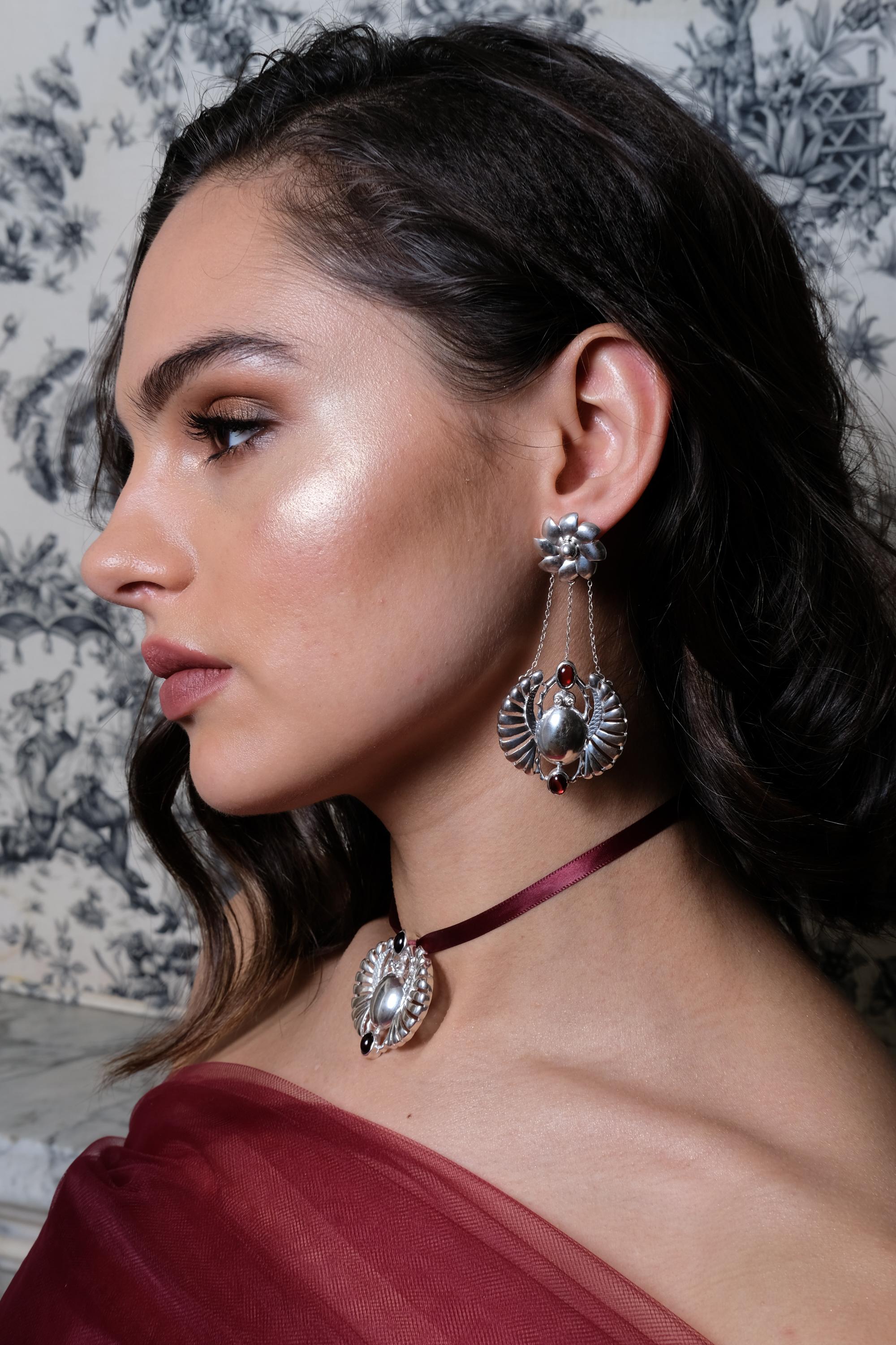 This pair of open winged scarab earrings are the sure way to make a statement to spark a cultural conversation. 18K Gold plated brass or Sterling silver
Gemstones: Cabernet Red Garnet, Lemon Citrine, chocolate diamond eyes.
Post earrings with broad