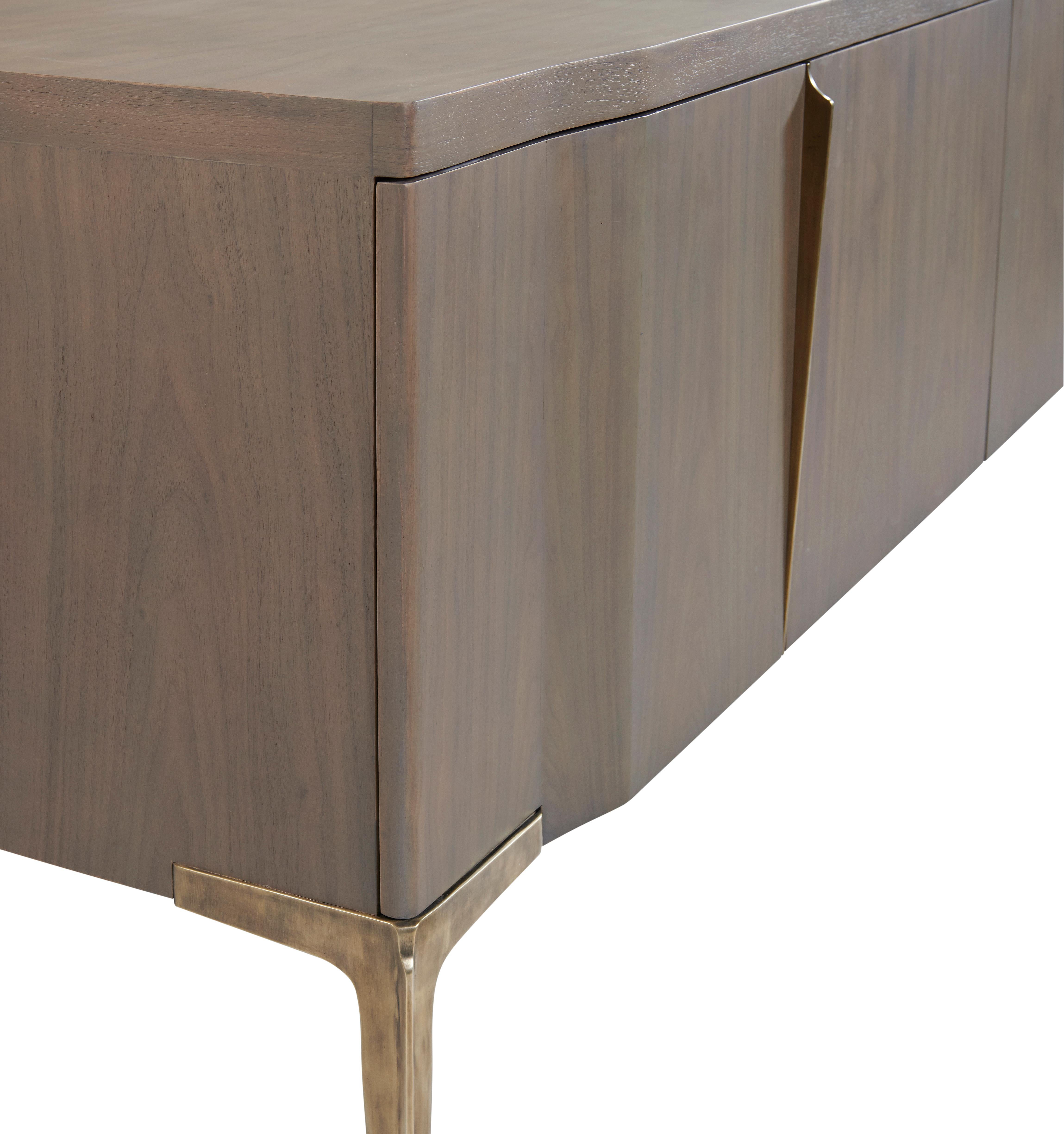 Khepera Credenza’s undulating door fronts and subtle pull reference the language of its slender and statuesque cast legs with their distinctive ridge detail which tapers down their length. This well-proportioned credenza also incorporates cable