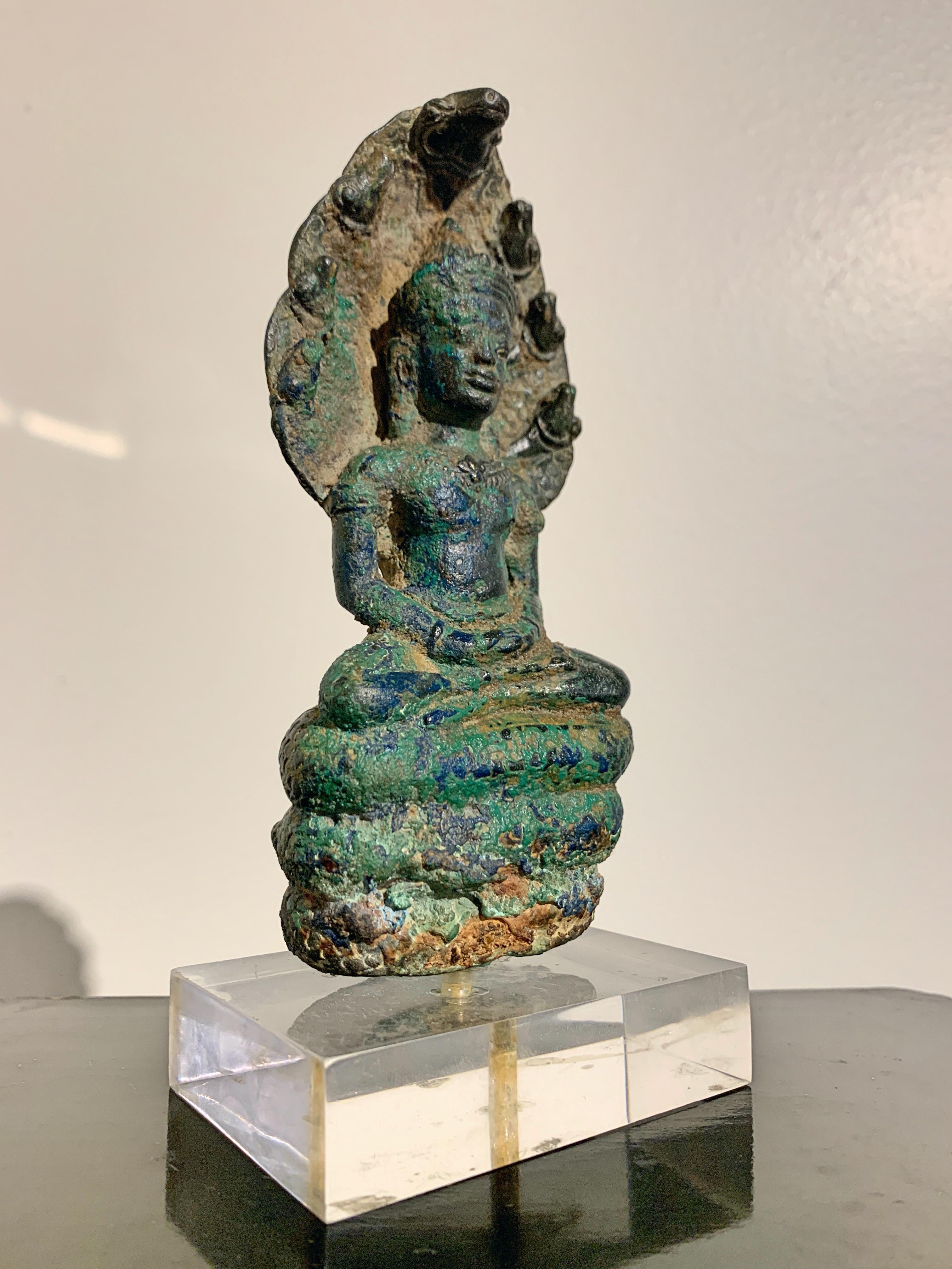 A wonderful small Khmer cast bronze figure of the Buddha sheltered by a Naga (Buddha Muchalinda), Angkor Period, style of the Bayon, late in the period, 14th century, Cambodia.

This small Khmer cast bronze sculpture is known as Buddha Muchalinda,