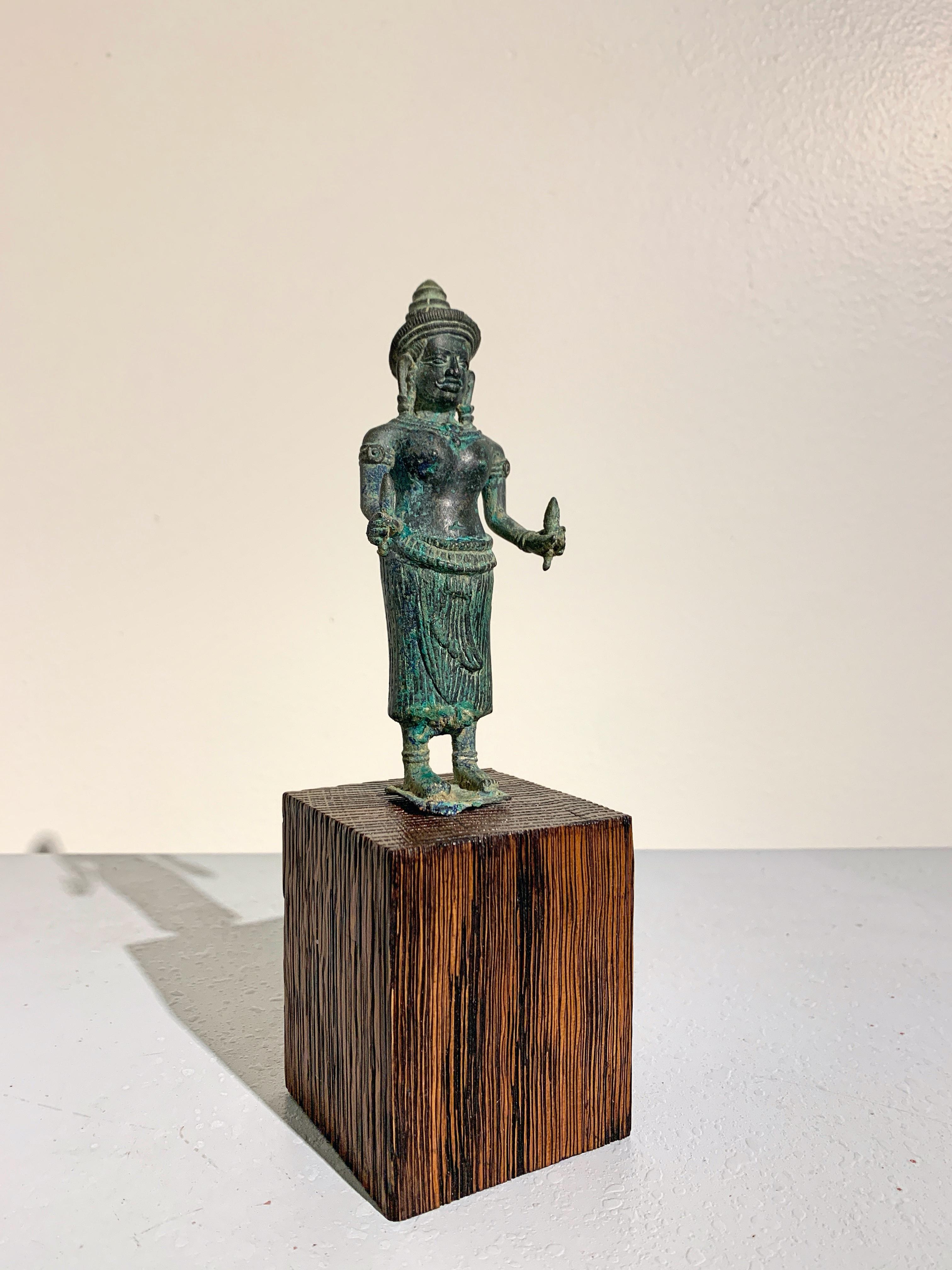 A small Khmer bronze figure of the Hindu goddess Uma, Angkor Period, Style of Angkor Wat, circa 12th century, Cambodia.

This small Khmer bronze devotional figure depicts the Hindu goddess Uma, consort of Shiva, goddess of love and beauty. She is