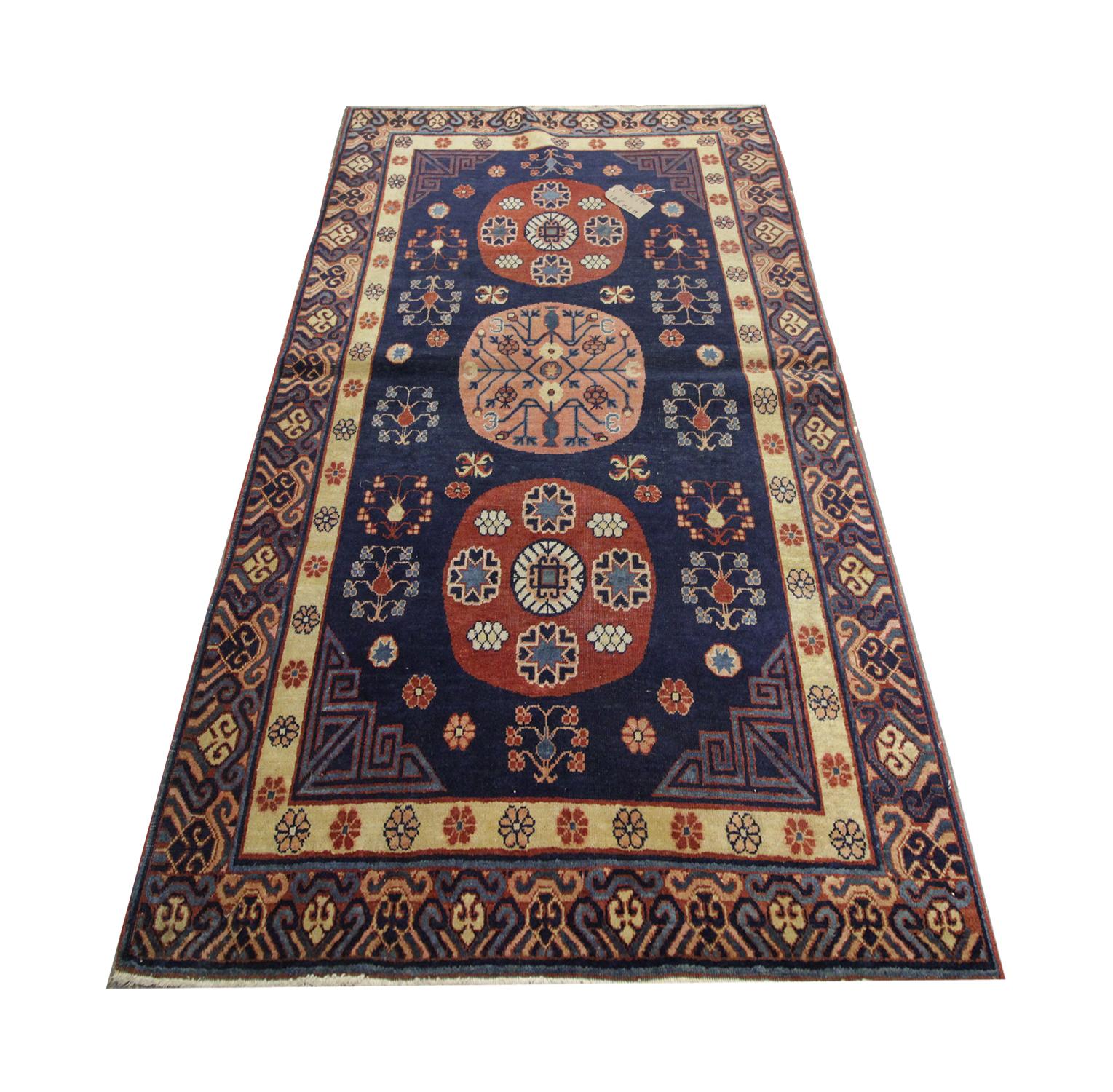 This handmade carpet Oriental rug deep blue central Asian antique rug was handwoven in Kohtan in 1989. Three circular emblems flow through the centre in red and peach, surrounded by geometric flower motifs. Enclosed by patterned corner designs and a