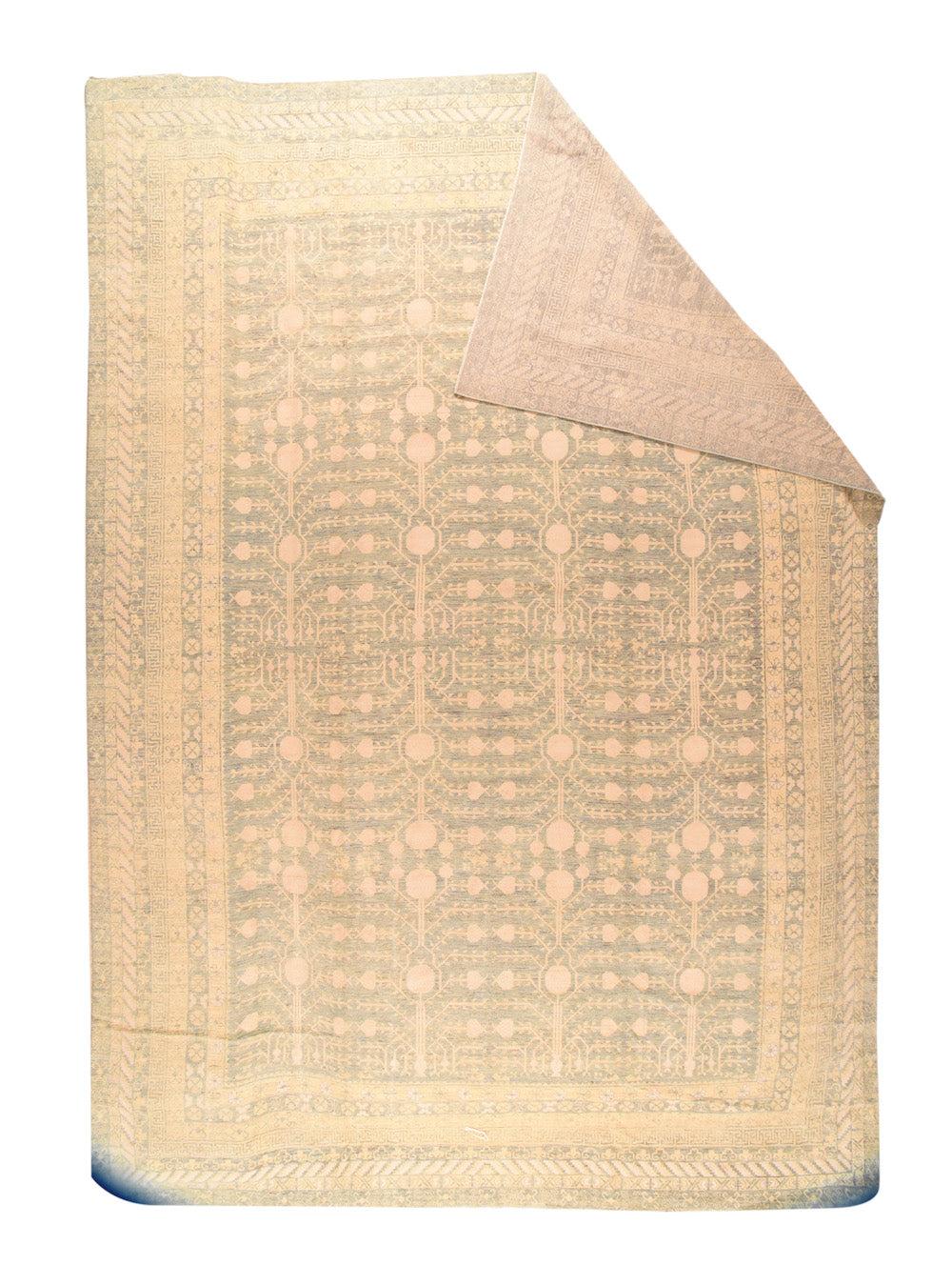 Khotan-Teppich 13'8'' x 19'7''. Das hellbraune Feld spielt mit dem charakteristischen Khotan-Vasen- und Granatapfelbaummuster, hier mit vier verzweigten und fruchttragenden Bäumen in jeder Feldhälfte. Mehrere schmale Bordüren, darunter ein 