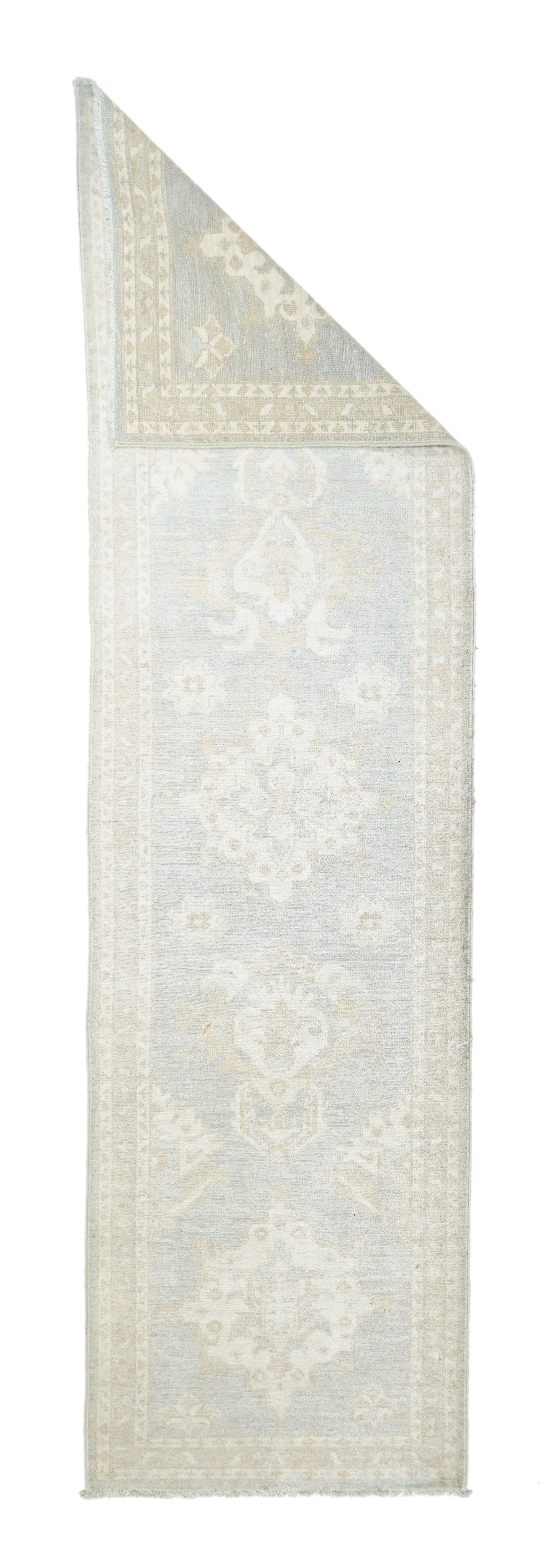 Tappeto Khotan 2'7'' x 9'5''. Le rosette spiccano, mentre le quattro corna d'ariete a raggiera in avorio antico si ritirano nel terreno marrone chiaro. Bordo principale con barre sottili inclinate e rosette, su sfondo crema. Ordito e trama in