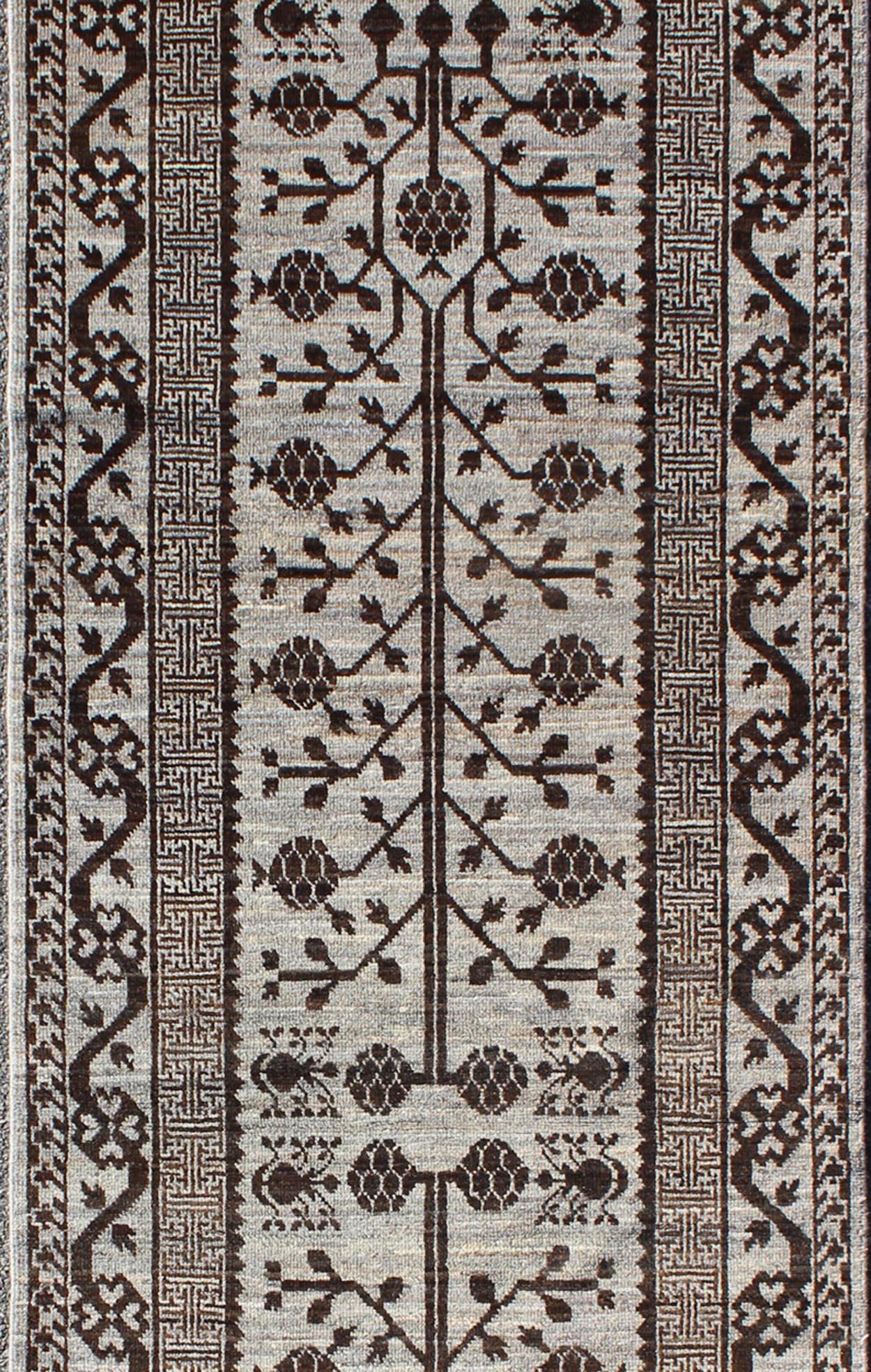 This Khotan features a geometric all-over design flanked by a repeating pattern in the border. The entirety of the piece is rendered in grey and brown which makes it a versatile rug, well-suited for a variety of interiors.

Measures: 3'0 x 9'9