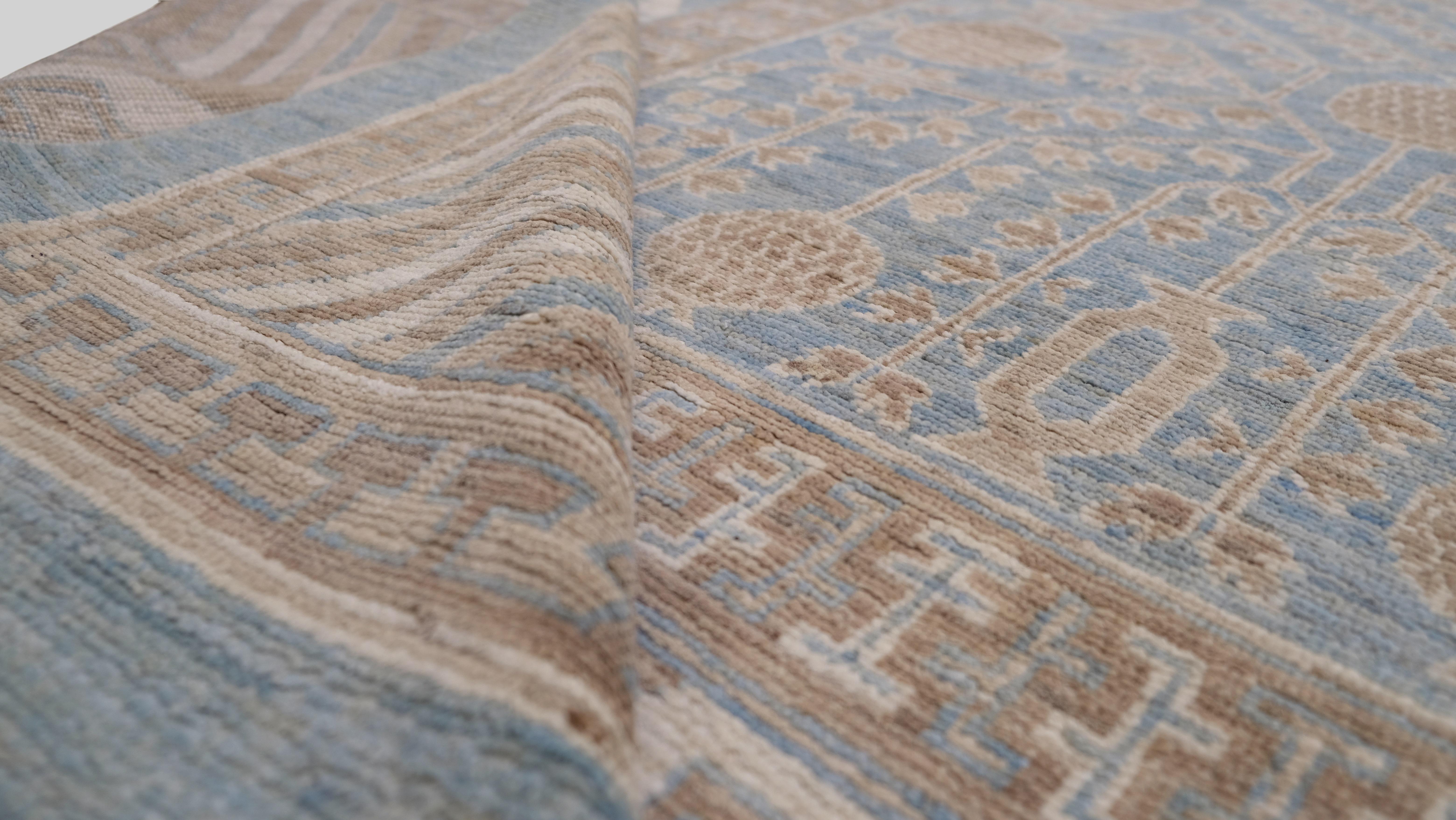Elevate your space with this hand-knotted wool rug, featuring a delicate blend of floral and geometric motifs in a sophisticated soft blue and beige color palette. The intricate pattern, inspired by traditional Persian and Central Asian designs,