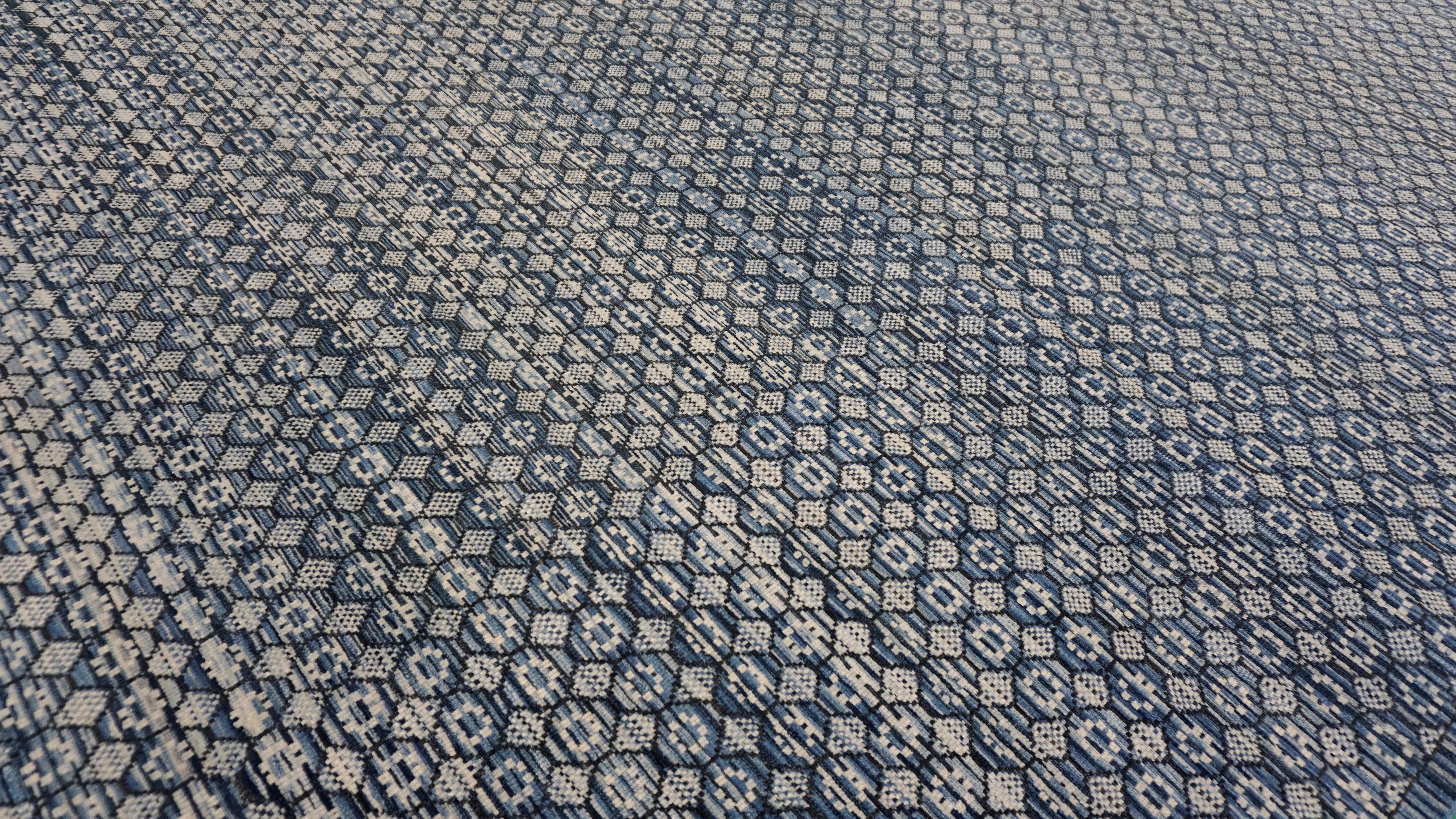 This hand-knotted wool rug features a finely rendered Khoton pattern, distinguished by its repeating octagonal and diamond motifs arranged in a symmetrical mosaic. The design draws inspiration from historic tribal weavings of Central Asia,