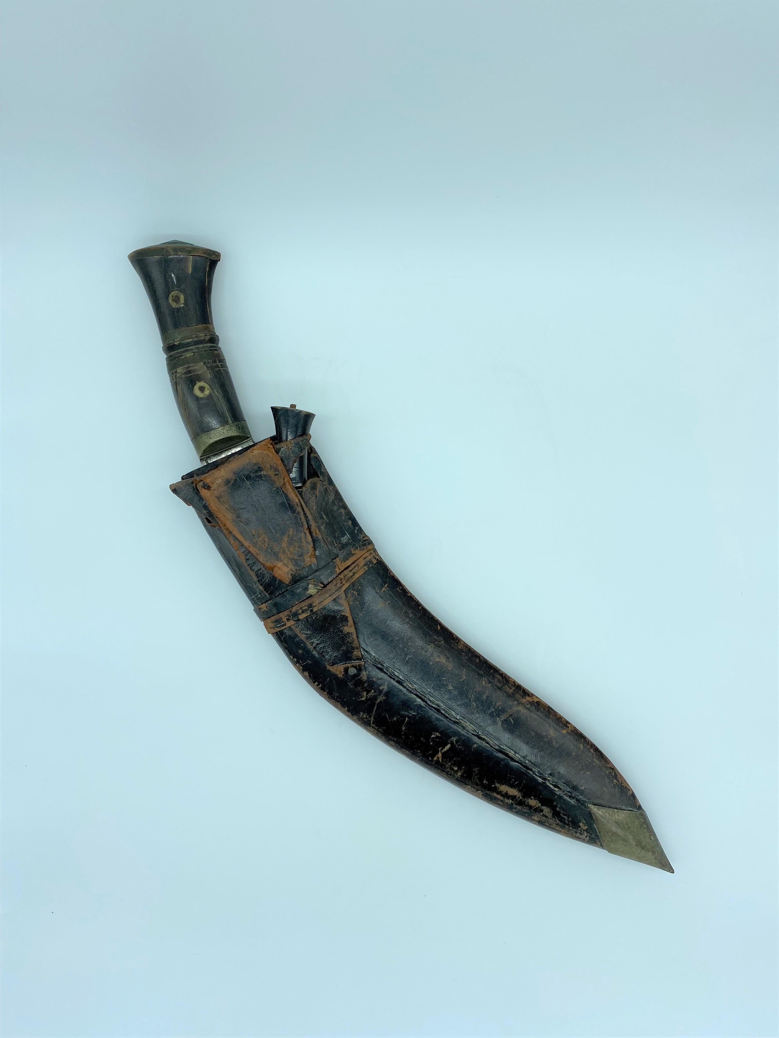 Khukuri knife from Nepal, early 20th century. 
Its blade is heavy and curved, made of forged metal. The handle is made from horn and copper. With it is attached a smaller Khukuri (measuring 1.9 inch x 4.3 inch).

The Khukuri is a Nepalese knife