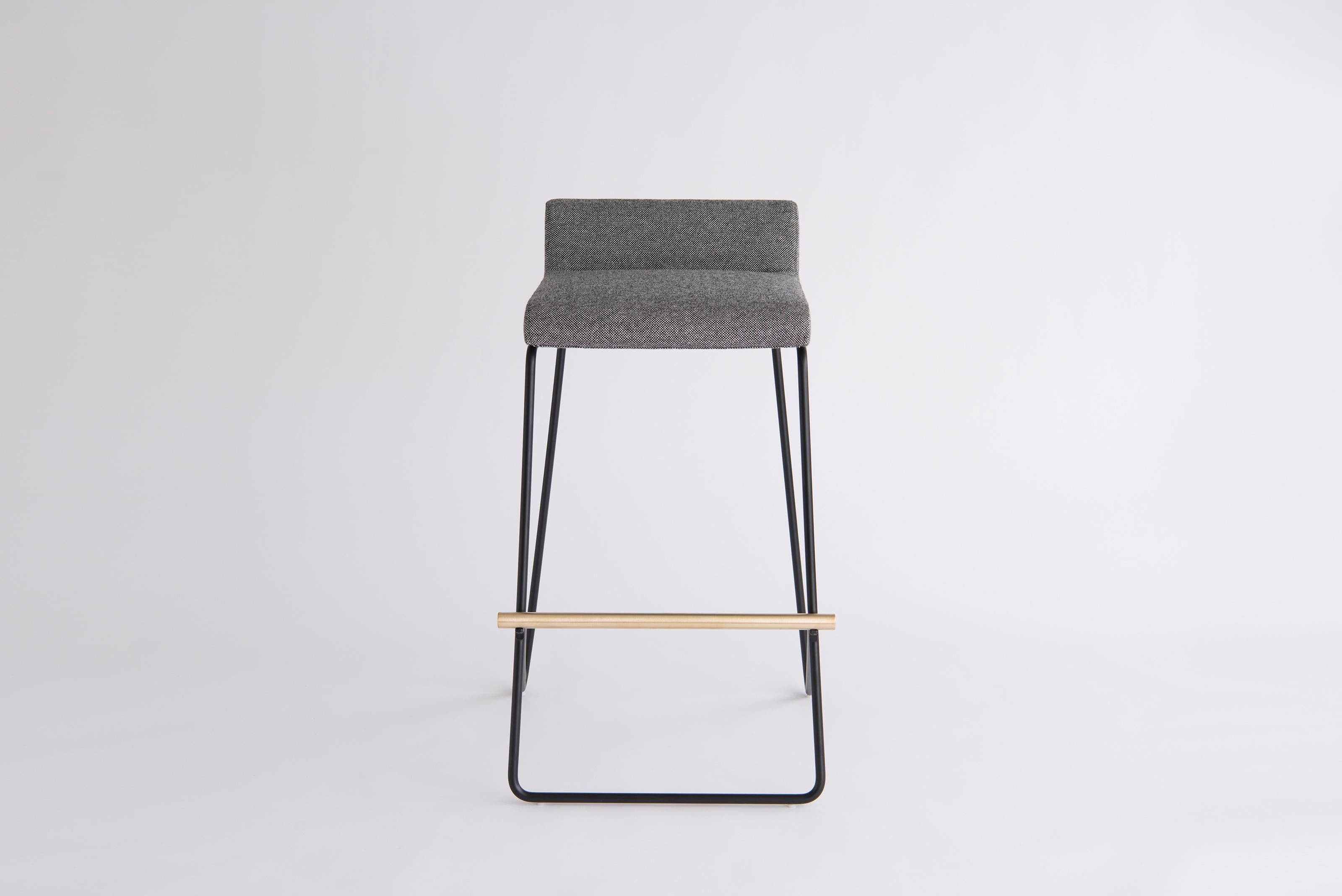 Kickstand Bar Stool by Phase Design
Dimensions: D 59.1 x W 55.2 x H 88.9 cm. 
Materials: Upholstery, powder-coated metal and brushed brass.

Solid steel bar available in a flat black or white powder coat finish with solid brushed brass bar and
