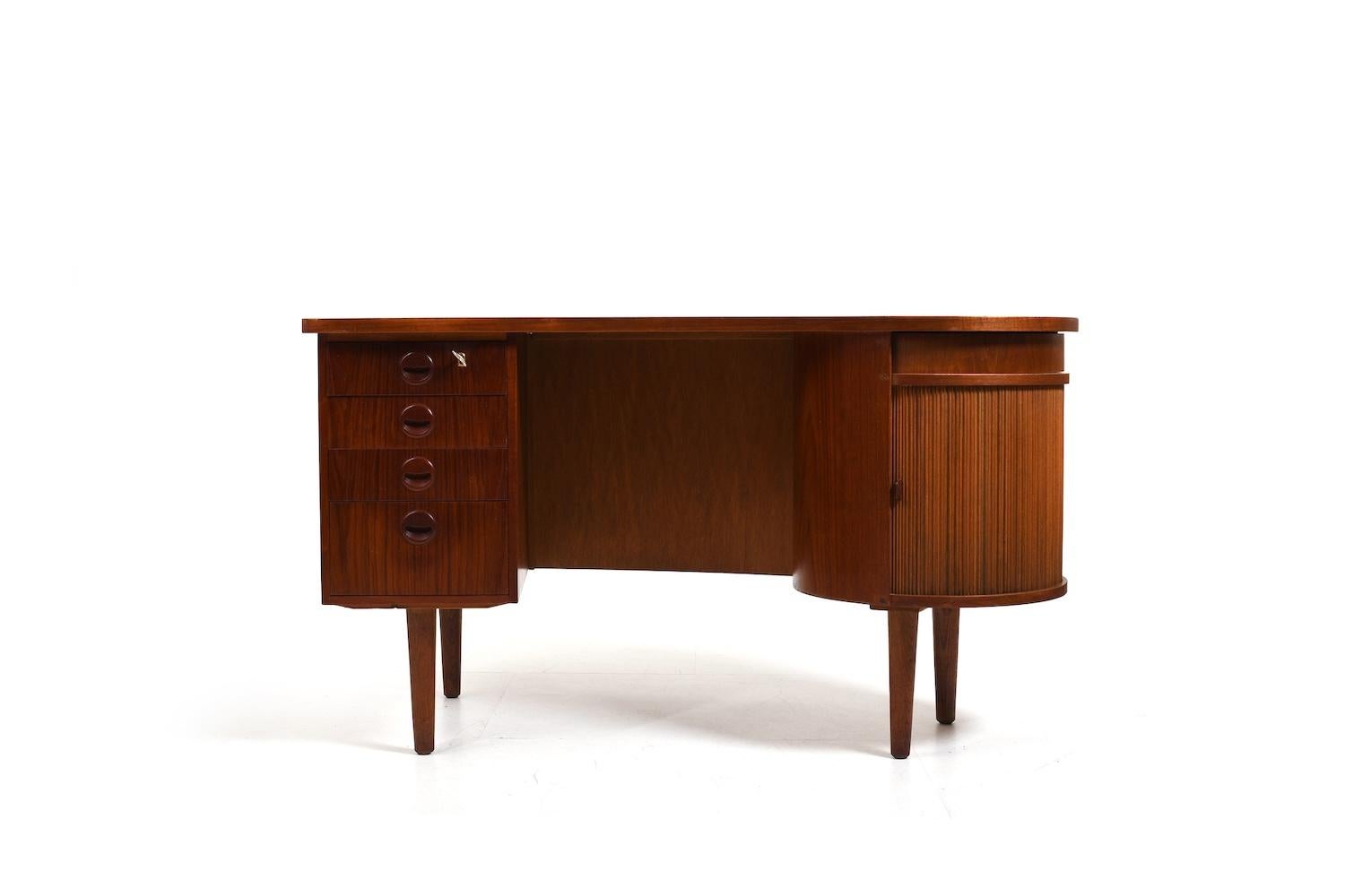 Freestanding teak kidney desk, model no.54 by Feldballes Møbelfabrik Denmark. Produced in 1950s  in teak. With 4 drawers, a tambour door on side and a rotating storage compartment with mirror. In front with bookshelves.