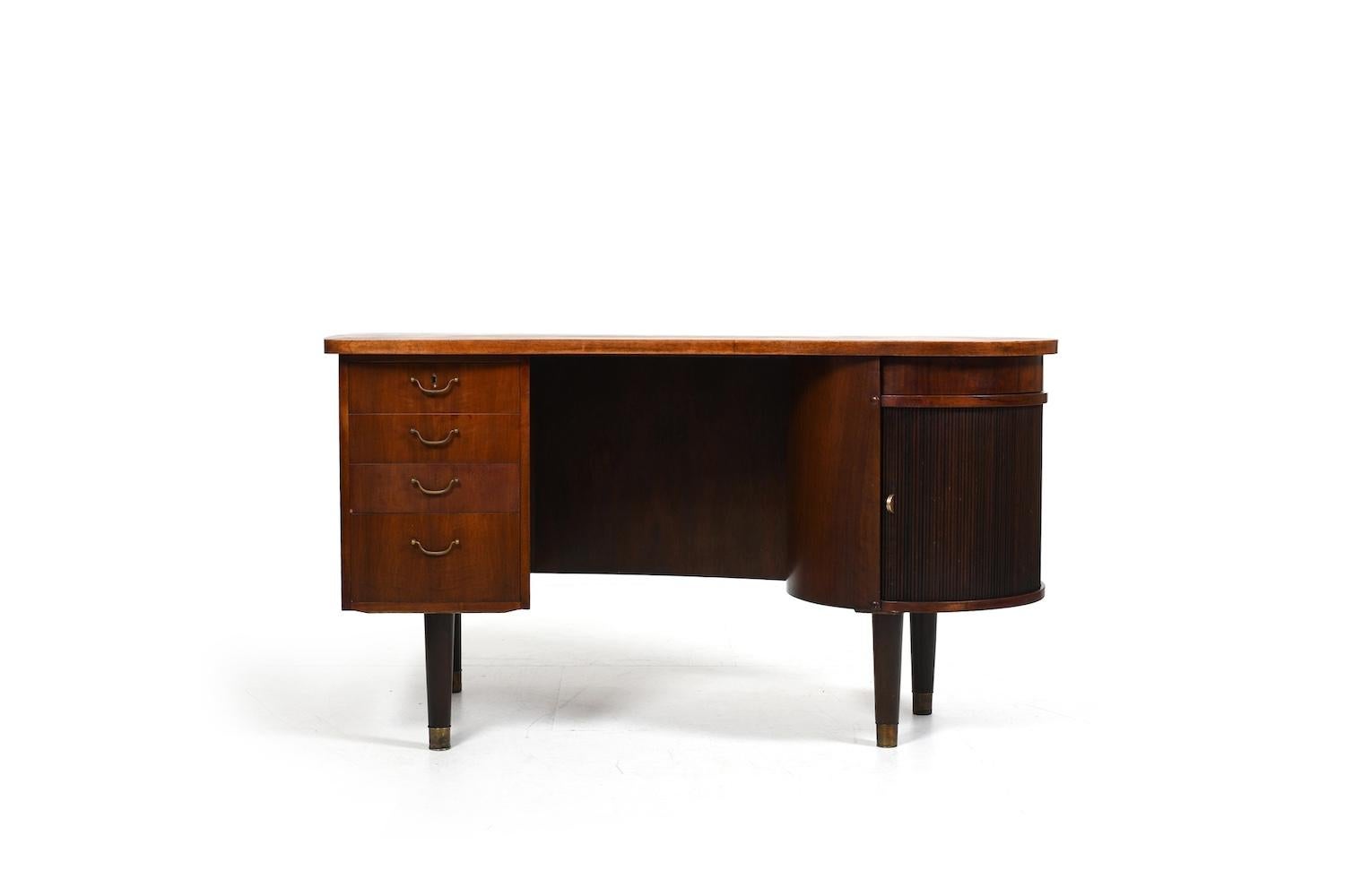 Old freestanding kidney desk, model no.54 by Feldballes Møbelfabrik Denmark. This desk is the early 1950s version in walnut, brass handles and brass shoes on the ends of the legs. Also with a shutter door on one side and a rotating storage