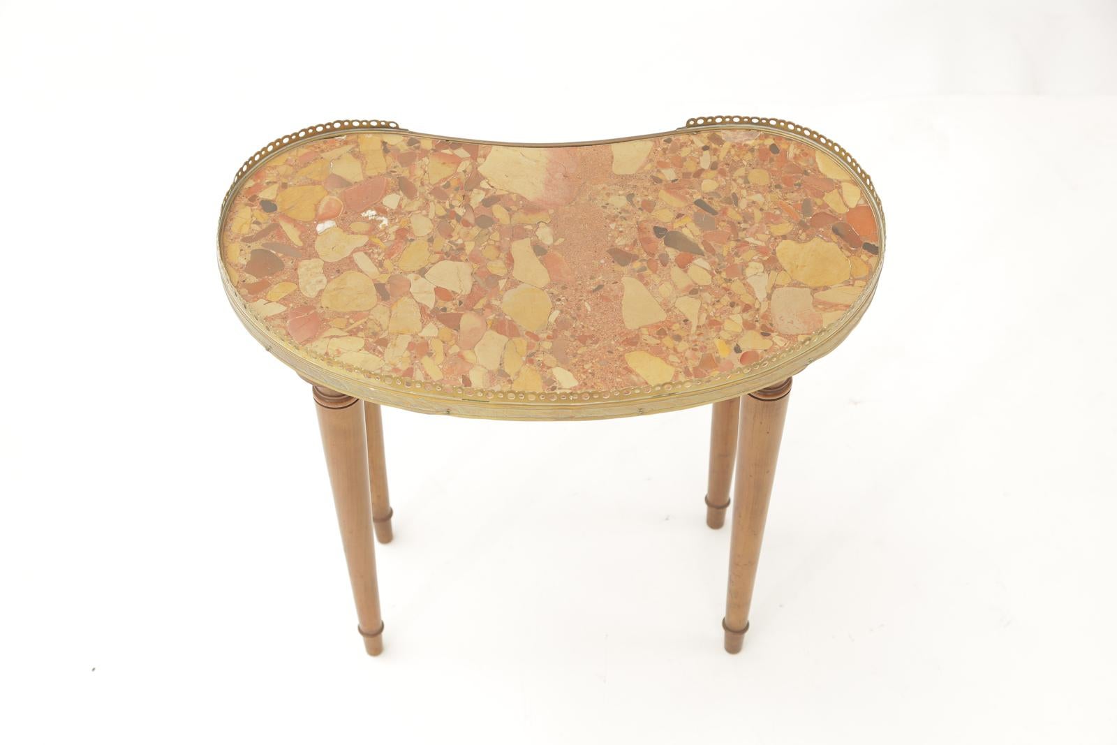 Table d'appoint à plateau réniforme en marbre Brèche d'Alep, bordé d'une galerie 3/4 en laiton percé, reposant sur des pieds ronds et effilés, terminés par des pieds toupies.

Stock ID : D3415.