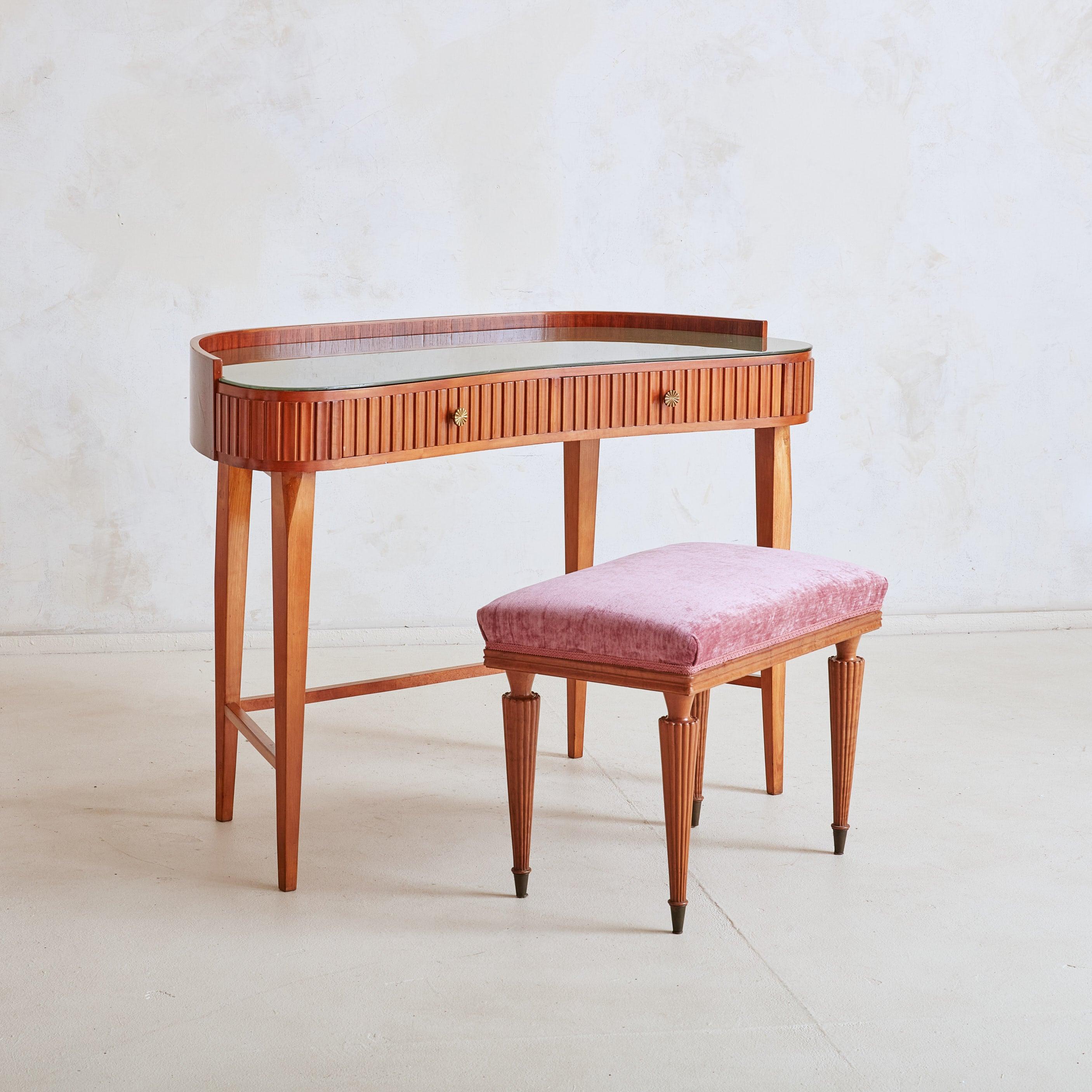 A charming 1950s vanity or petite writing desk in the style of Italian architect and furniture designer Paolo Buffa. Crafted from solid wood in a rich finish, it stands gracefully on four tapered legs and features an elegantly curved, raised back