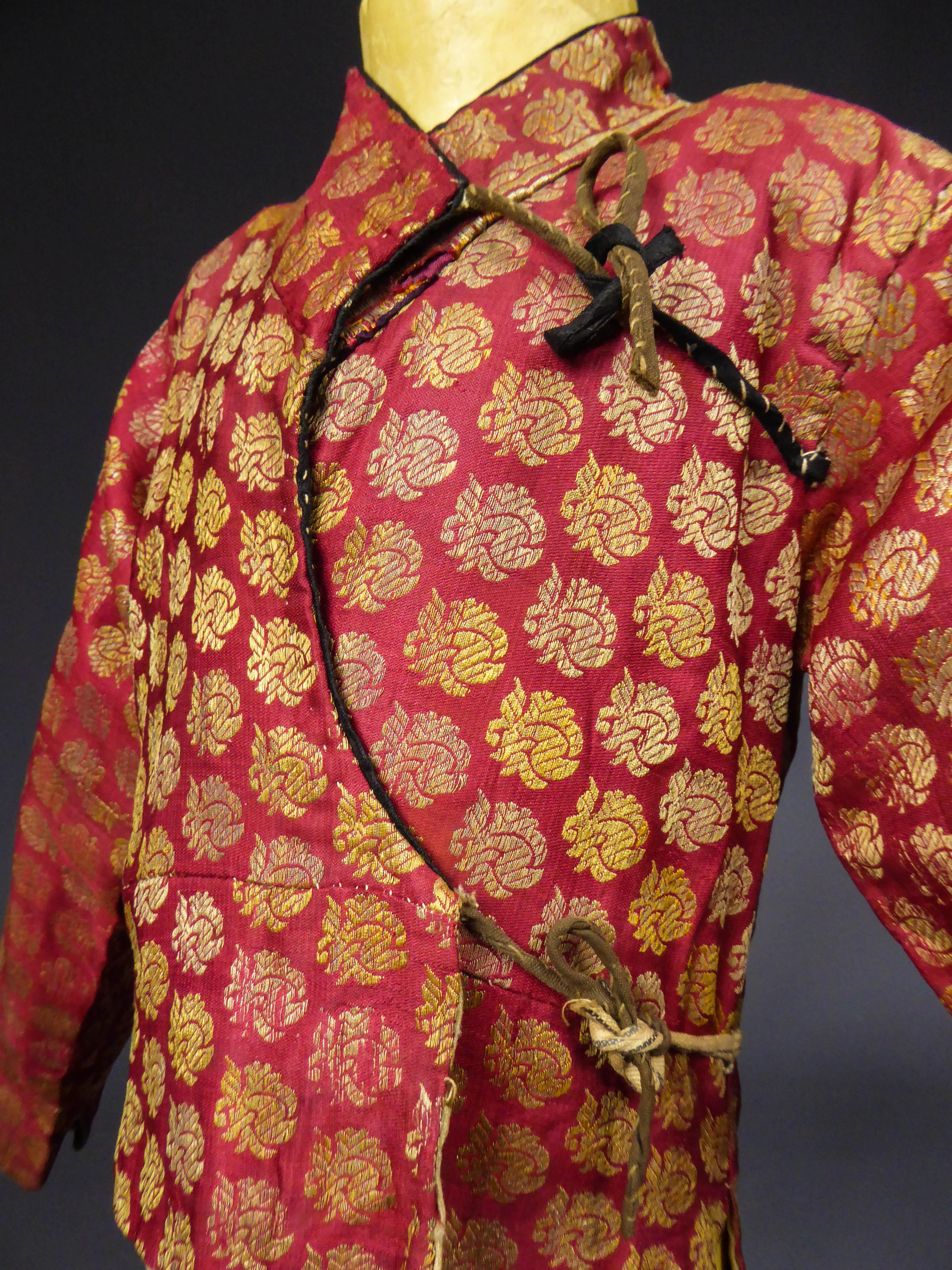 ​19th century
Persian 

Kid's jacket Kadjar in gold silk brocaded lampas dating quite early in the nineteenth century. Older silk and probably Safavid cherry color. Collar and piped cuffs with green taffeta and black taffeta. Cross ties on the front