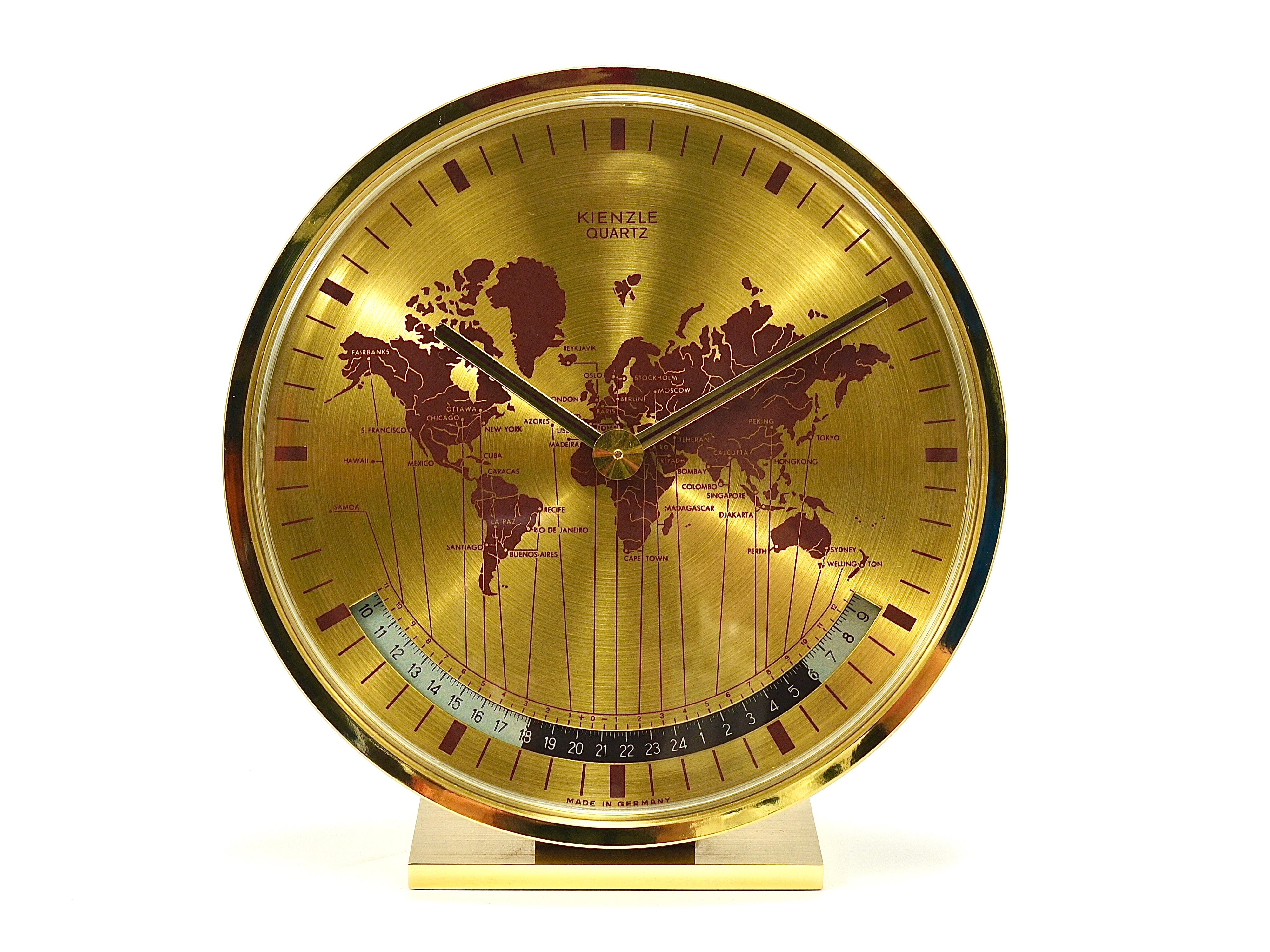 A beautiful and decorative Mid-Century Modernist solid brass Kienzle desk or table clock with a world map clocks face and world time zones. Executed in the 1960s by Kienzle in Western Germany. The housing and the base are made of solid brass. An