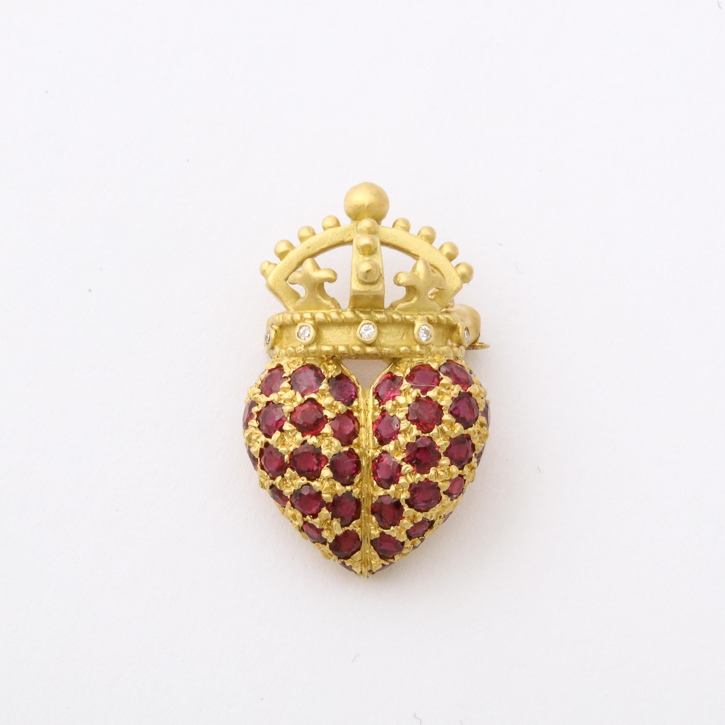 Exquisite Brooch in the manner of luxury jewelry designer Barry Kieselstein -Cord. It features a puffy crowned heart design in 18k yellow brushed gold . The crown has 5 bezel set round brilliant diamonds and the heart is set with 52 pave set rubies